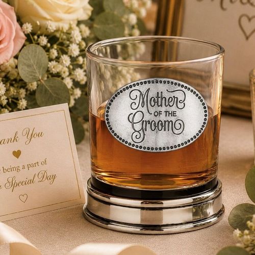 Whisky tumbler with pewter 'Mother of the Groom' badge and polished base, partially filled with amber liquid