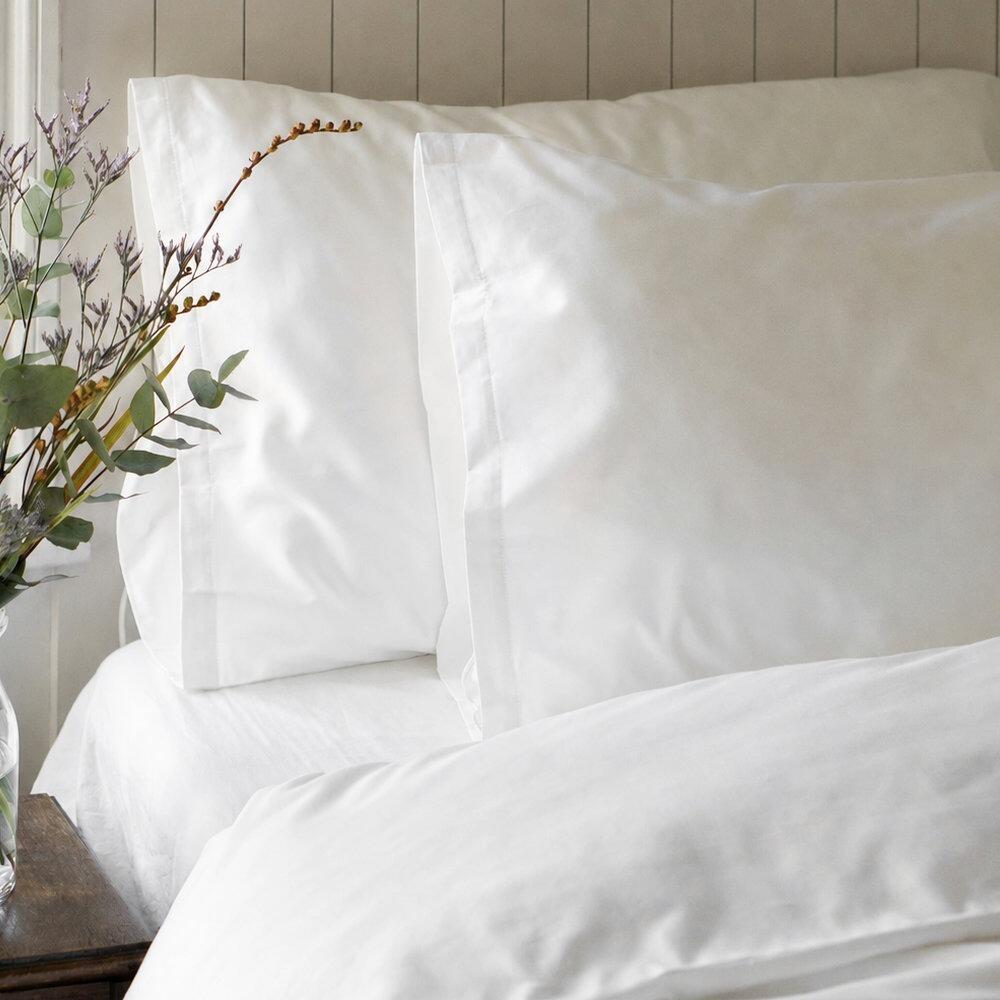 White super king pillowcase on a bed with floral styling