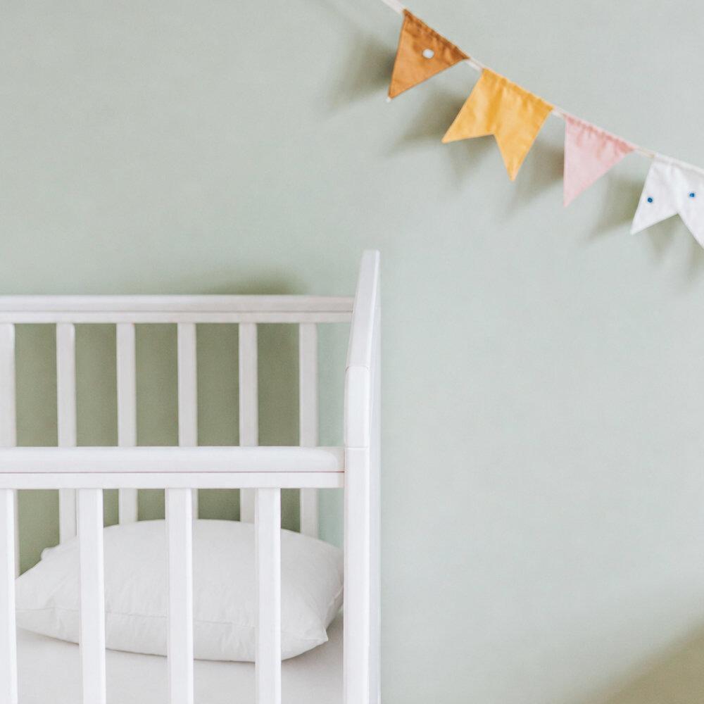 White cot pillow shown in a nursery cot
