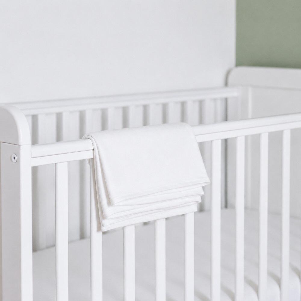 White cot pillowcases folded over side of cot bed