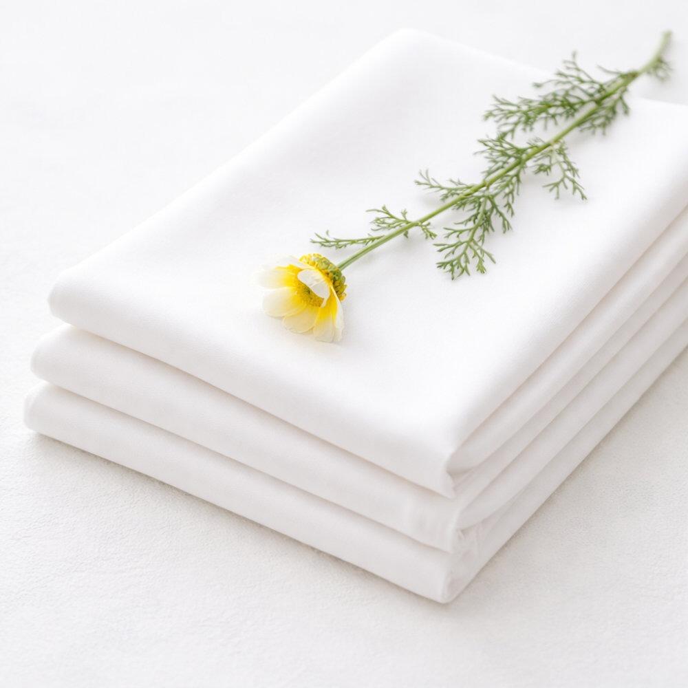 White cotton cambric fabric folded in a pile with a flower on top
