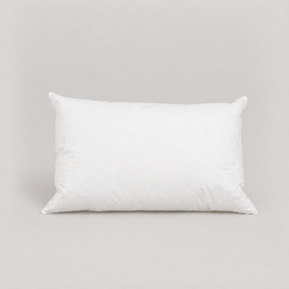 White cot bed pillow with top-stitched edges standing upright