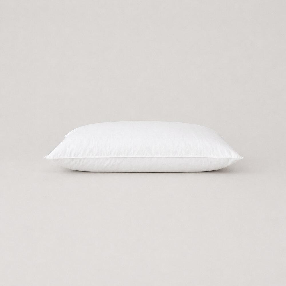 White cot pillow with top-stitched edges lying flat