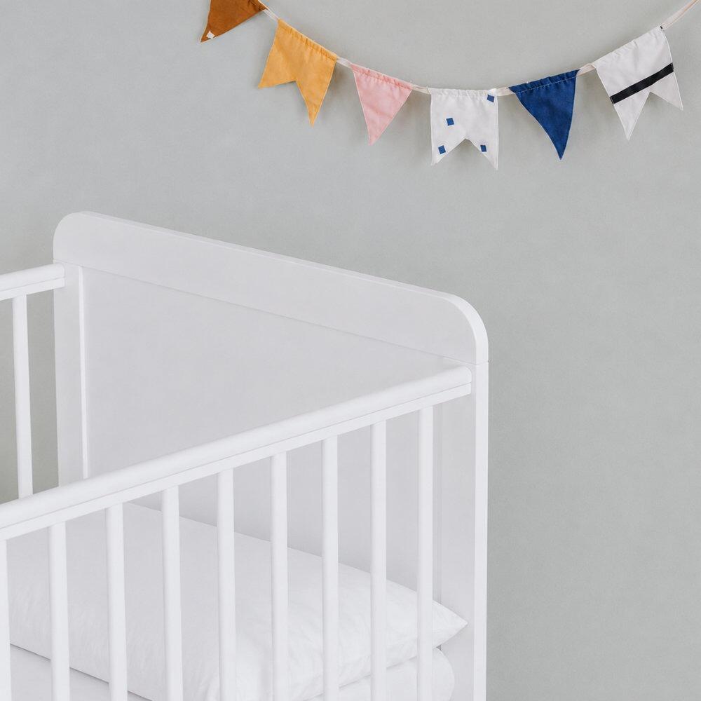White cot bed pillow shown in a cot bed