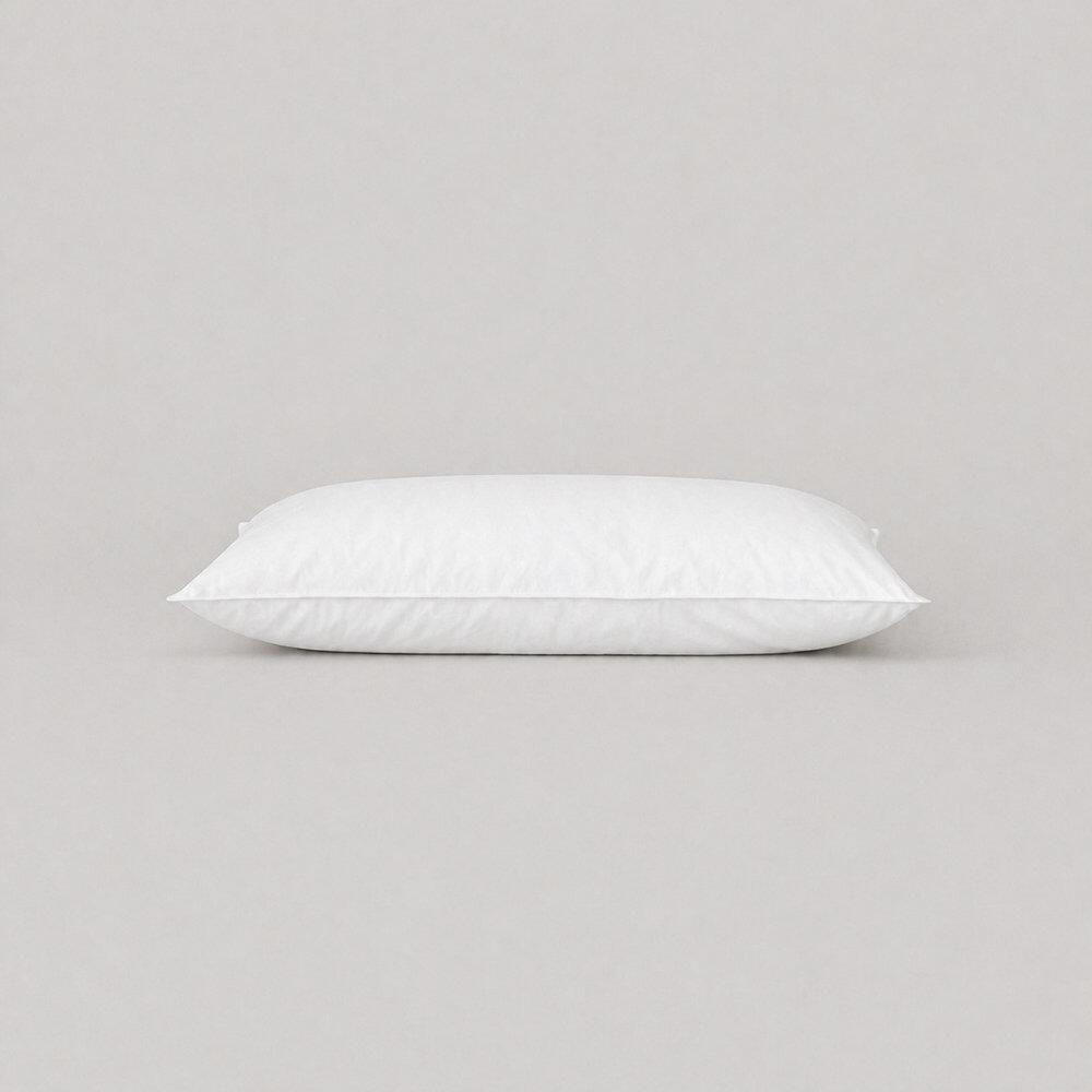 White cot bed pillow with top-stitched edges lying flat
