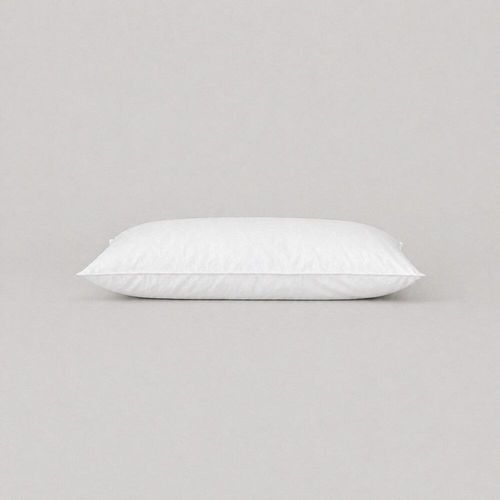 White cot bed pillow with top-stitched edges lying flat