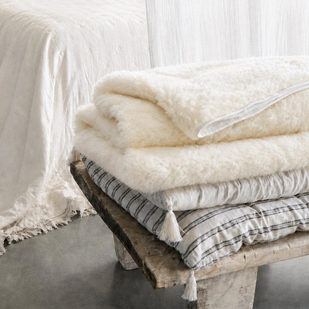 Wool mattress topper styled on cushions on a bench