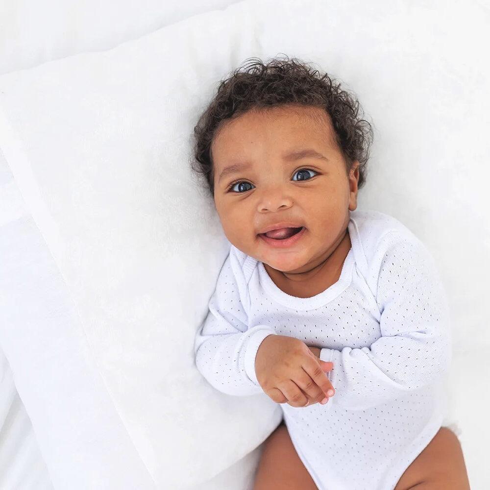 Baby lying on a white cot pillow