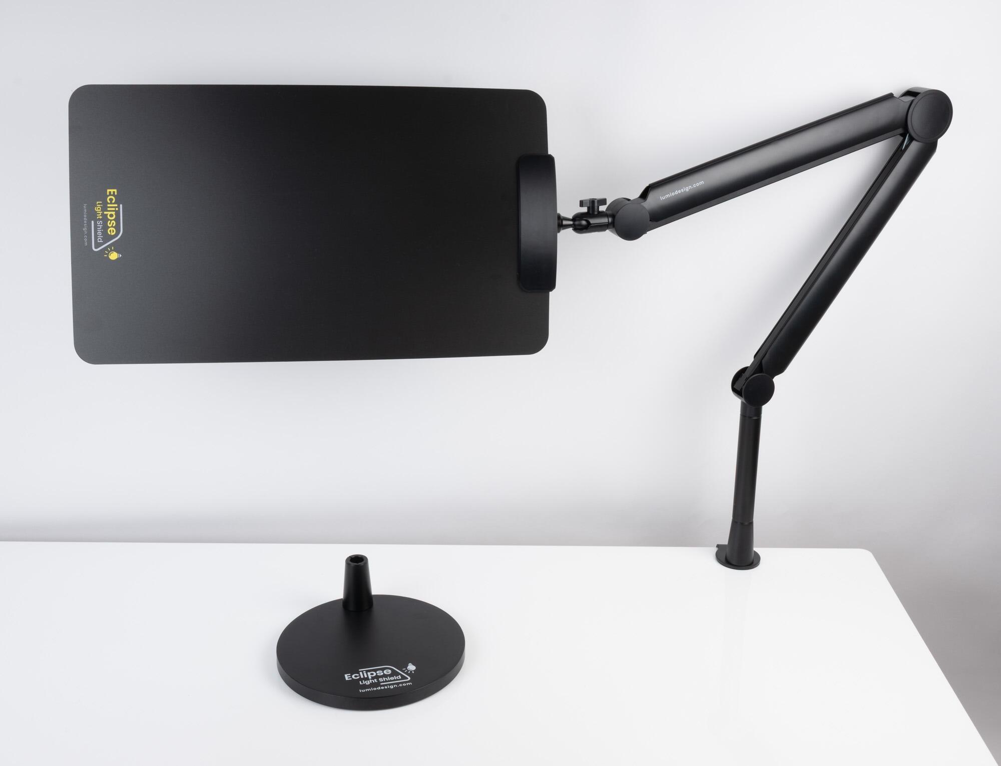 Eclipse Light Shield showing it clamped to a desk with the optional weighted base in the foreground