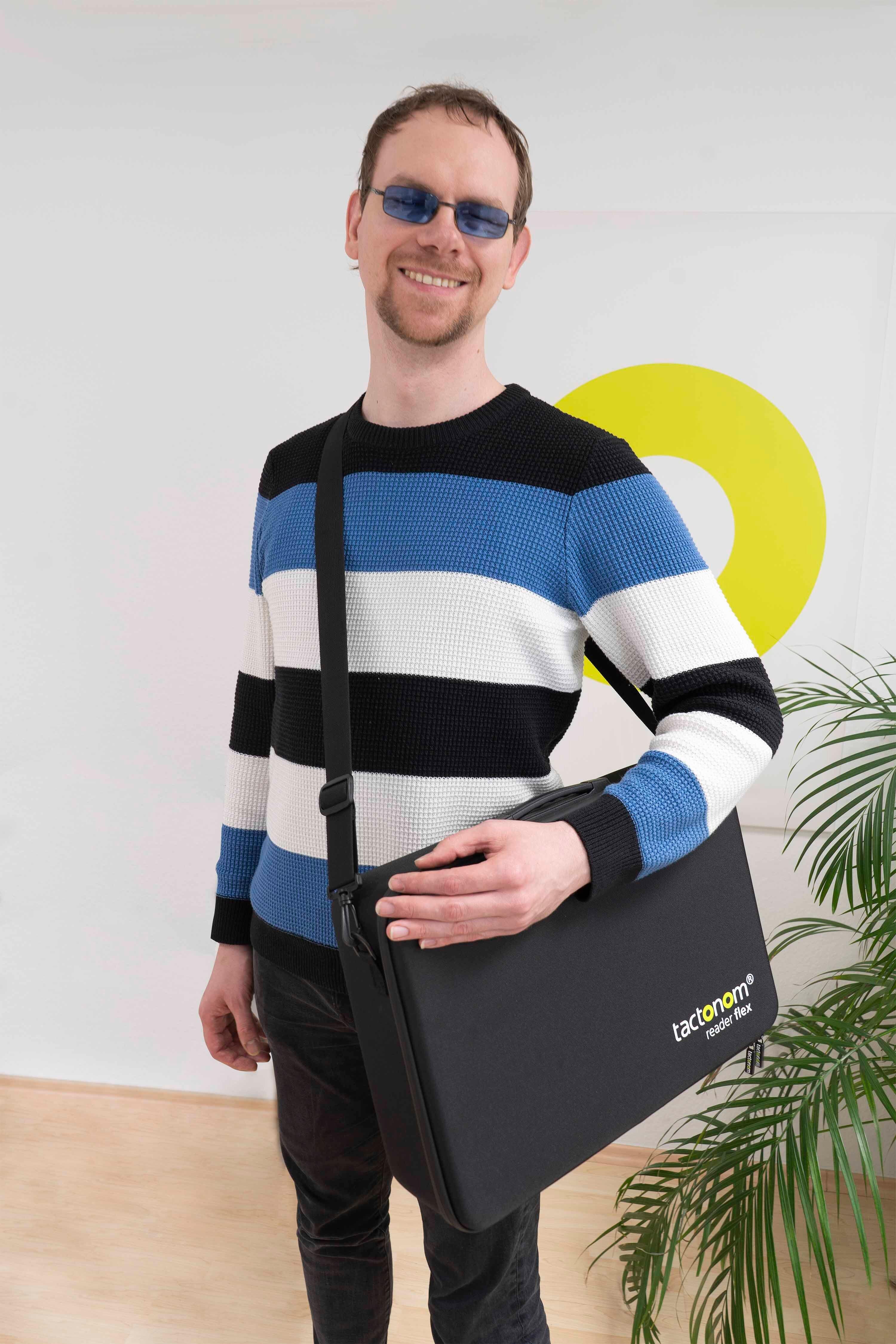A smiling man with the Tactonom Reader Flex Carry Bag on his shoulder