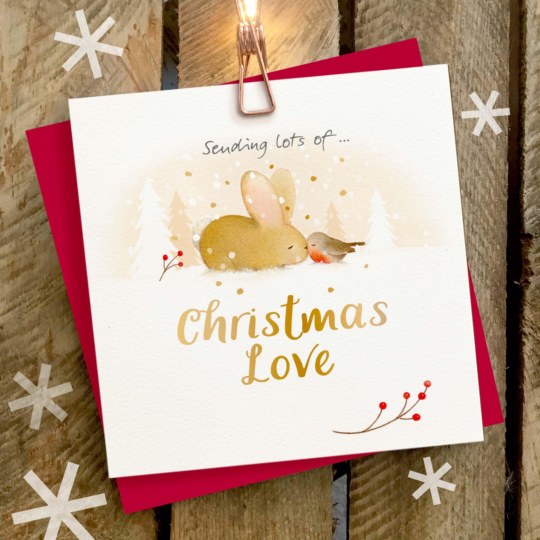 Christmas card featuring a large gold foil ‘Christmas Love’ caption with a rabbit and robin snuggling.