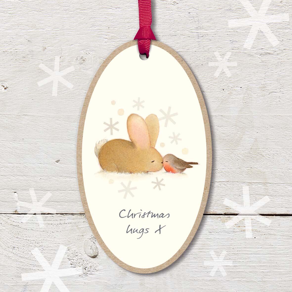 Large Christmas Wooden Plaque with attached red ribbon, featuring a cute baby rabbit and robin friend snuggling each other, with a ’Christmas Hugs’ caption.