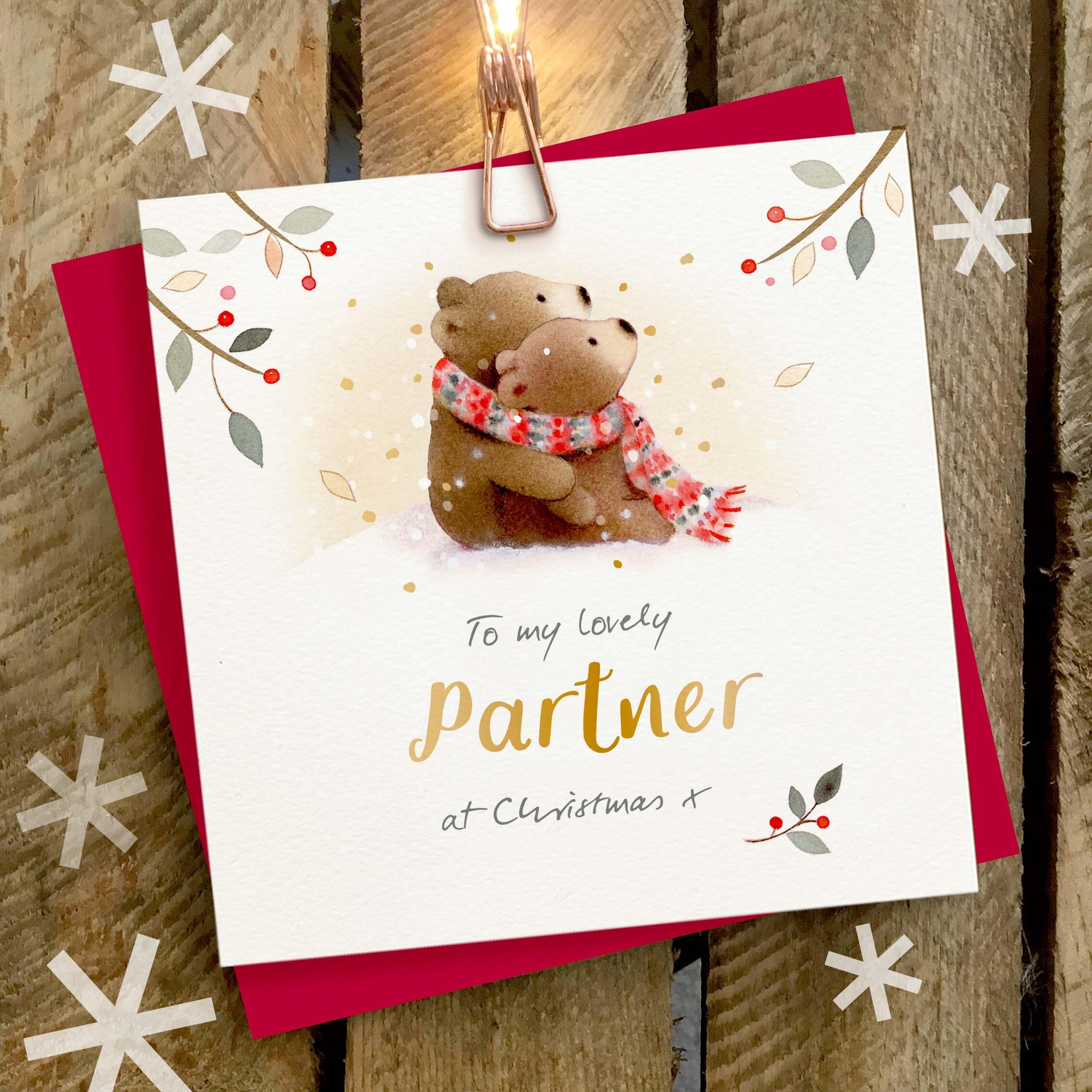 Christmas card featuring a large gold foil ‘Partner’ caption and a cute brown bear couple, wearing one large scarf.