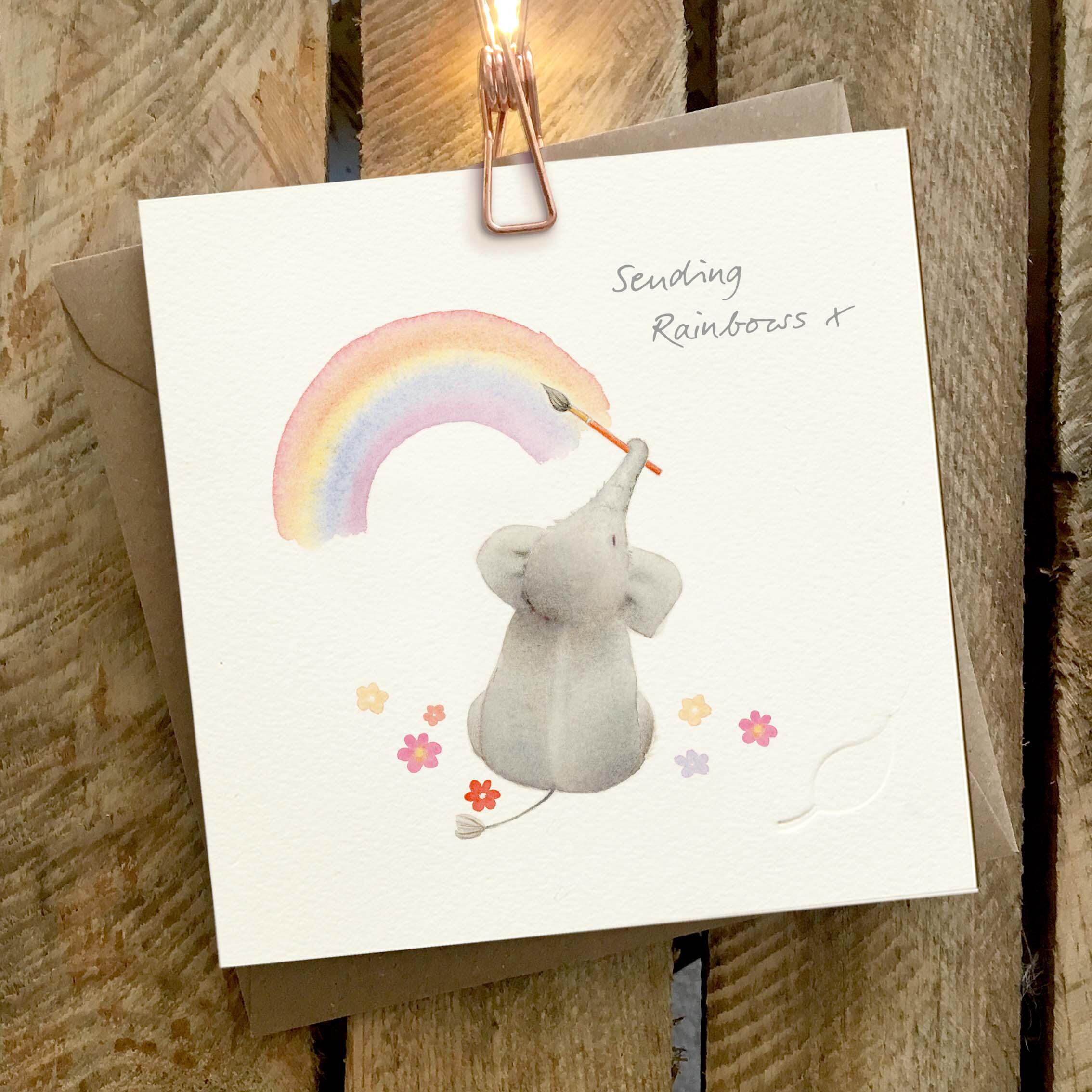 Elephant Family - Charity greeting card featuring a cute illustrated elephant, holding a paintbrush and painting a rainbow with its trunk.