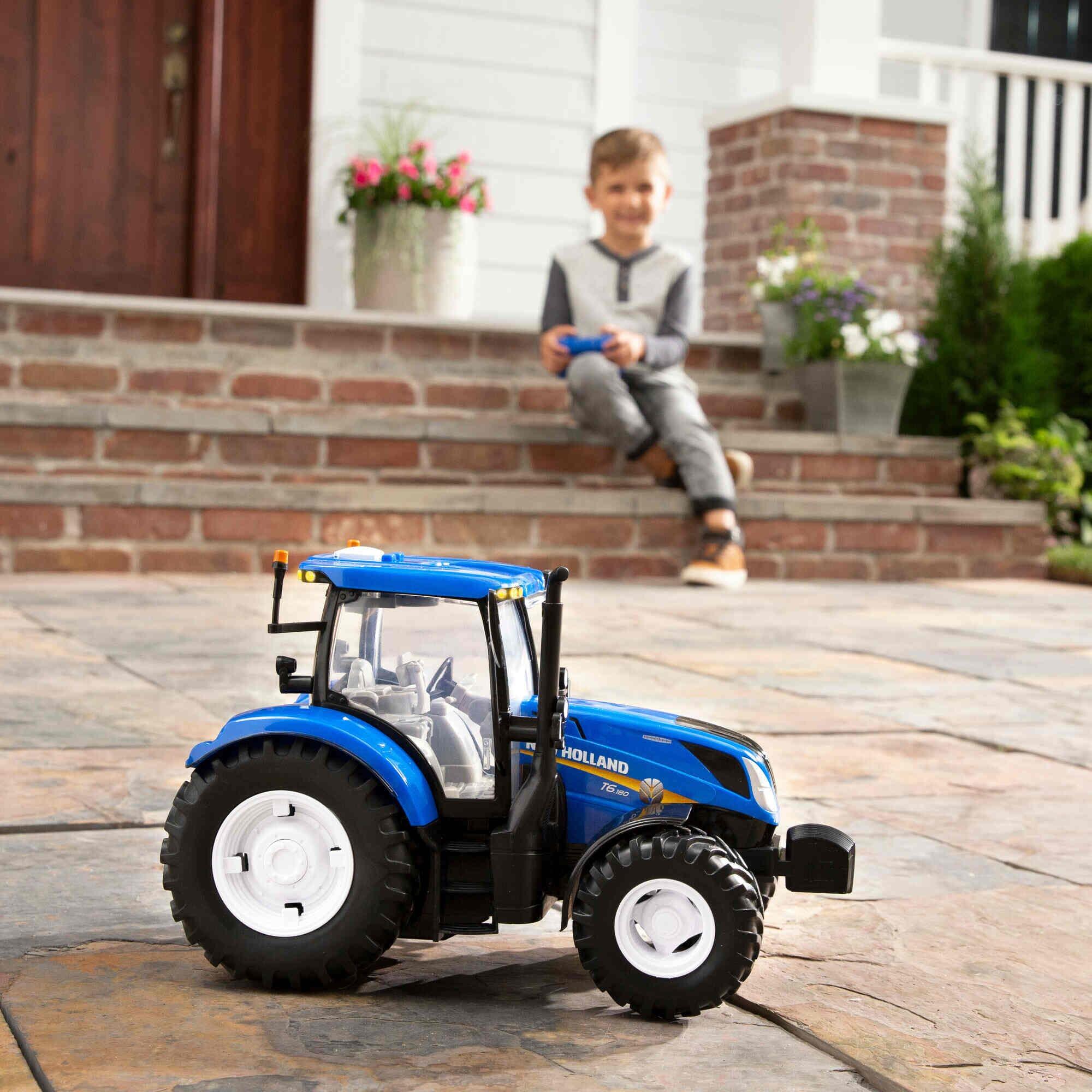 Boy driving Britains RC New Holland T6.180 tractor on patio