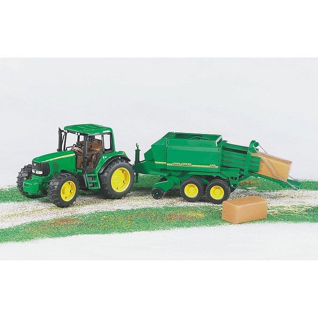 Green baler attachment connected to a tractor, with straw bales on the ground