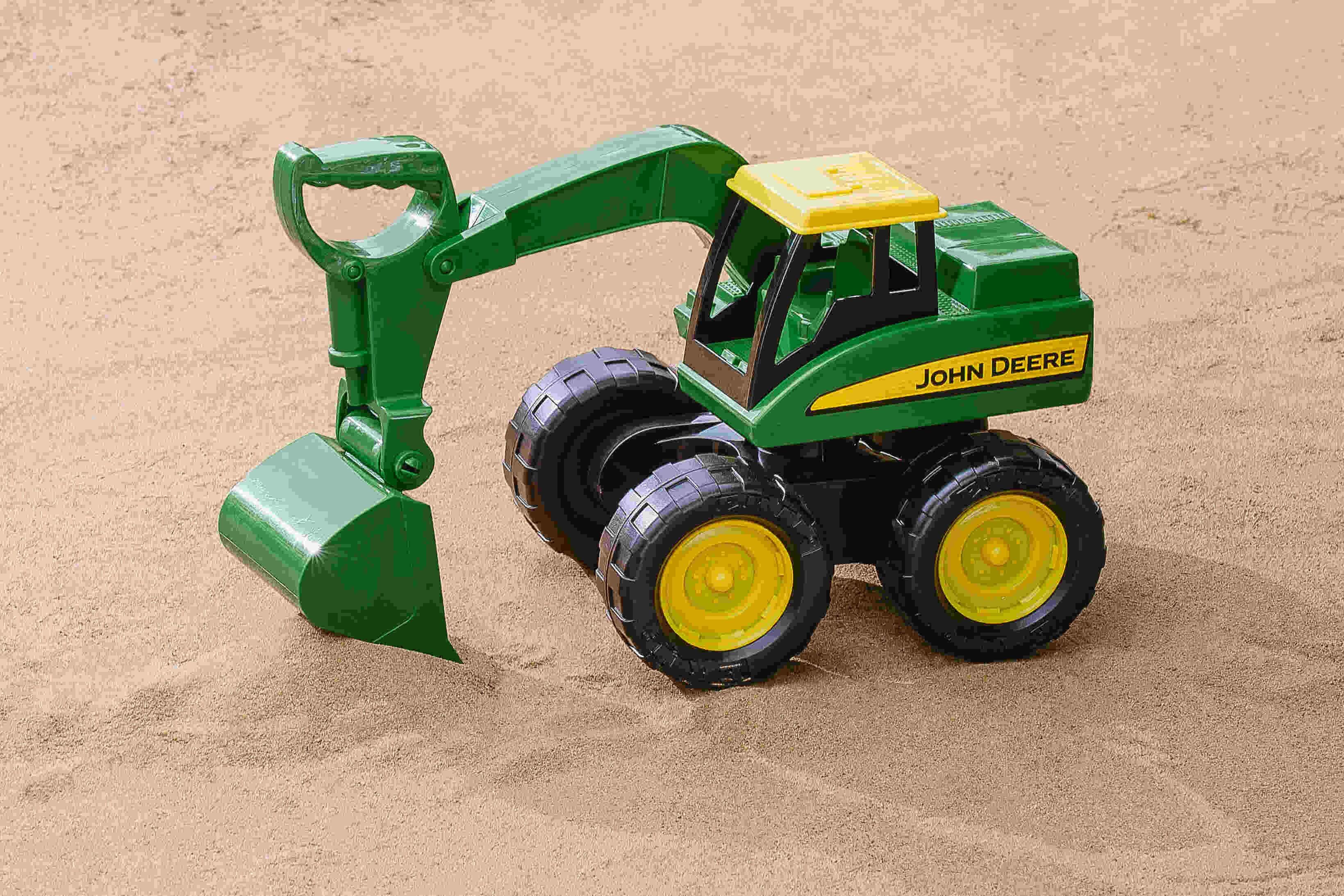 John Deere Big Scoop excavator toy pictured on sand with the scoop raised.