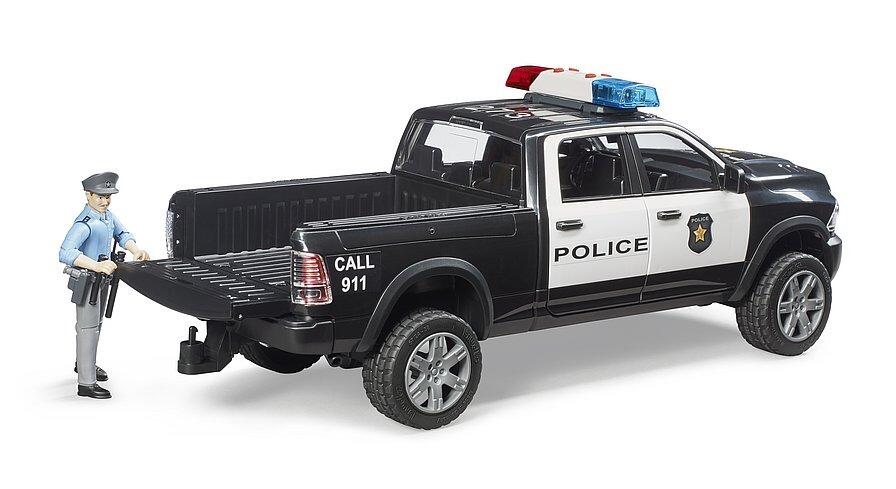 Rear view of Bruder RAM 2500 police pickup toy with open load bed and police officer standing behind truck