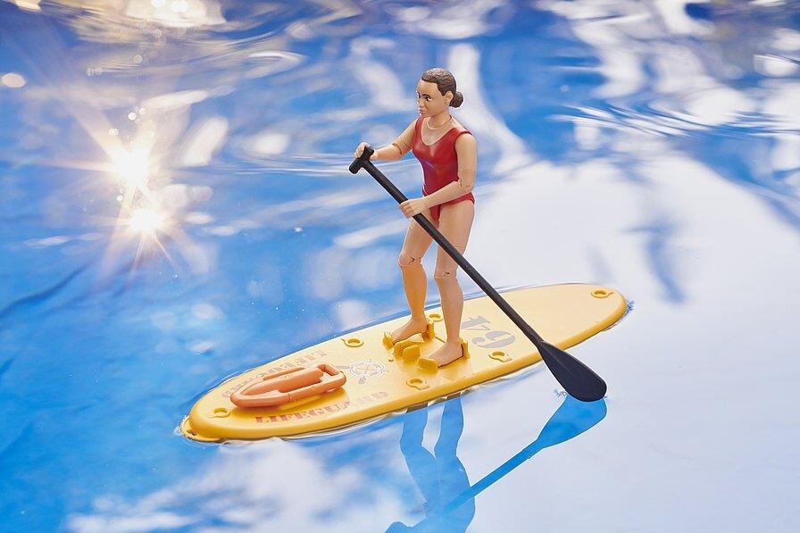 Bruder lifeguard on floating paddle board in water during lifeguard rescue play scene.