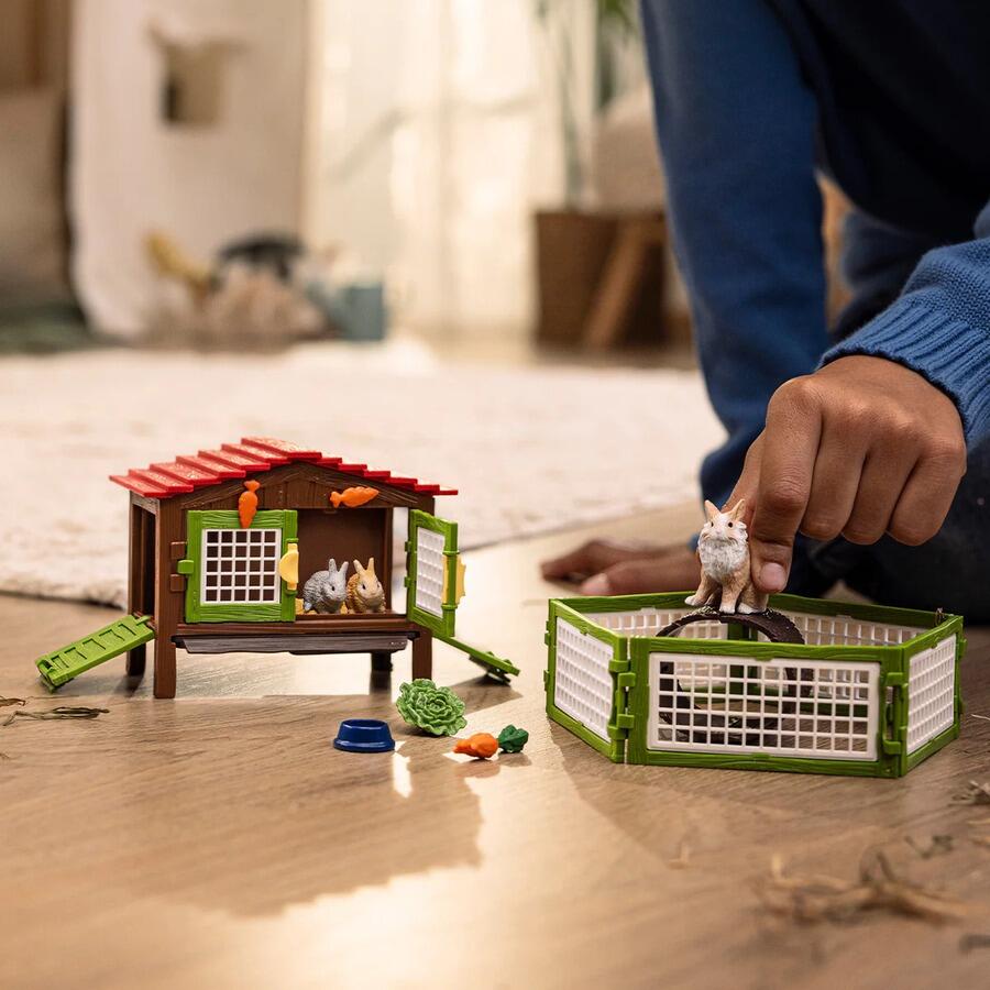 Child playing with the Schleich Rabbit Hutch with 3 Rabbits set on a wooden surface.