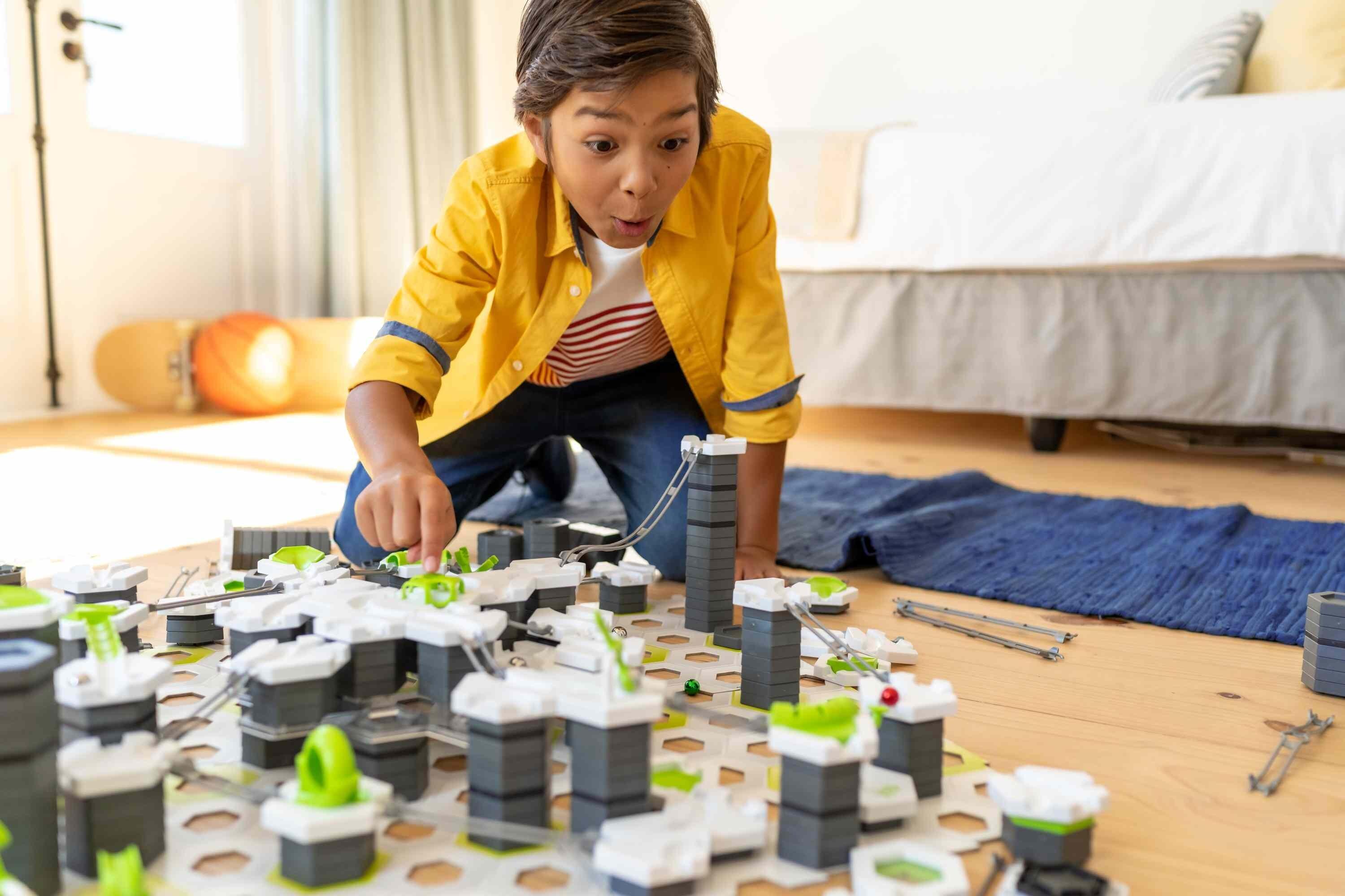 Child playing with a large GraviTrax marble run layout using Trax Pack components
