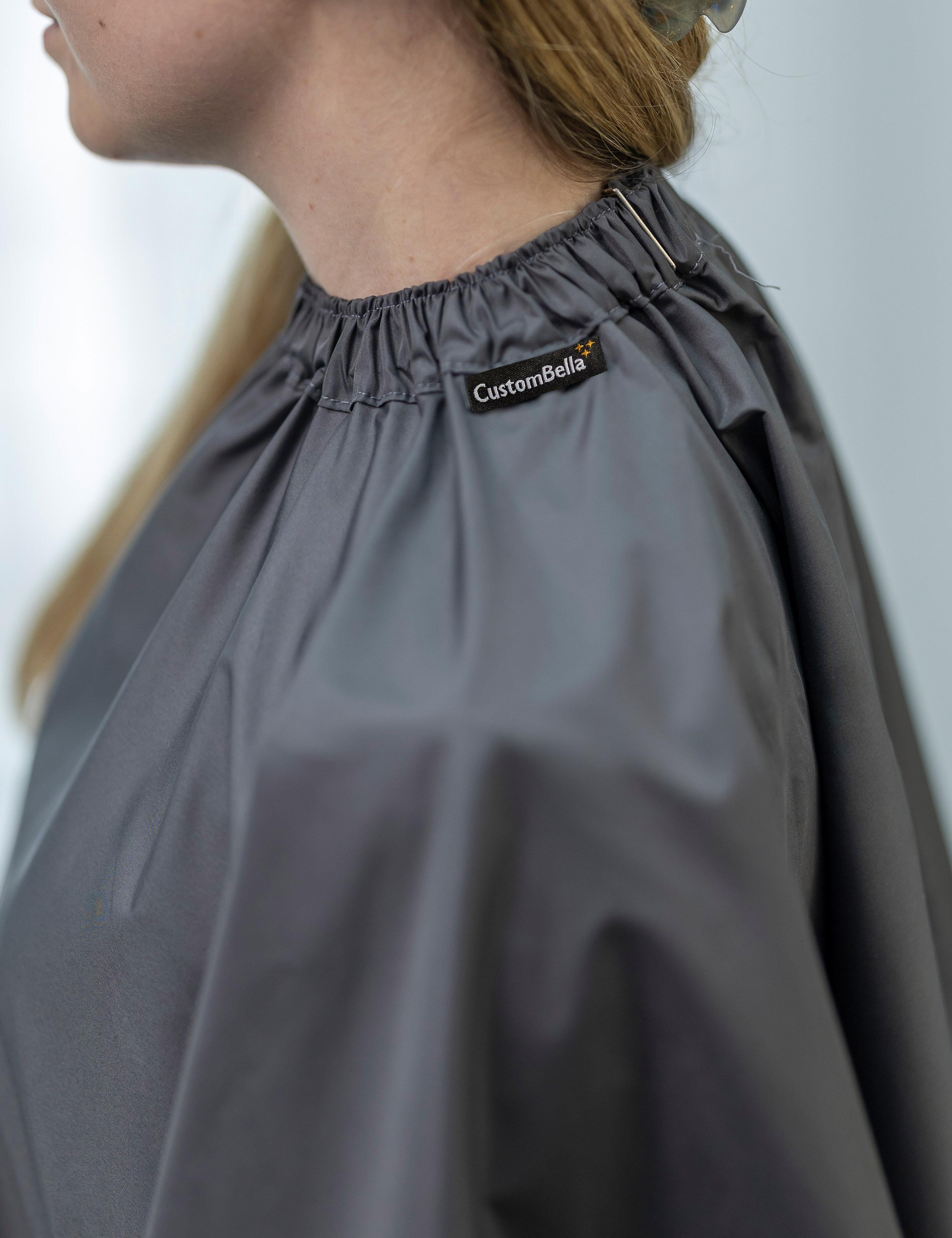 Dark grey barber cape with hand slits fitted with secure metal neck clips