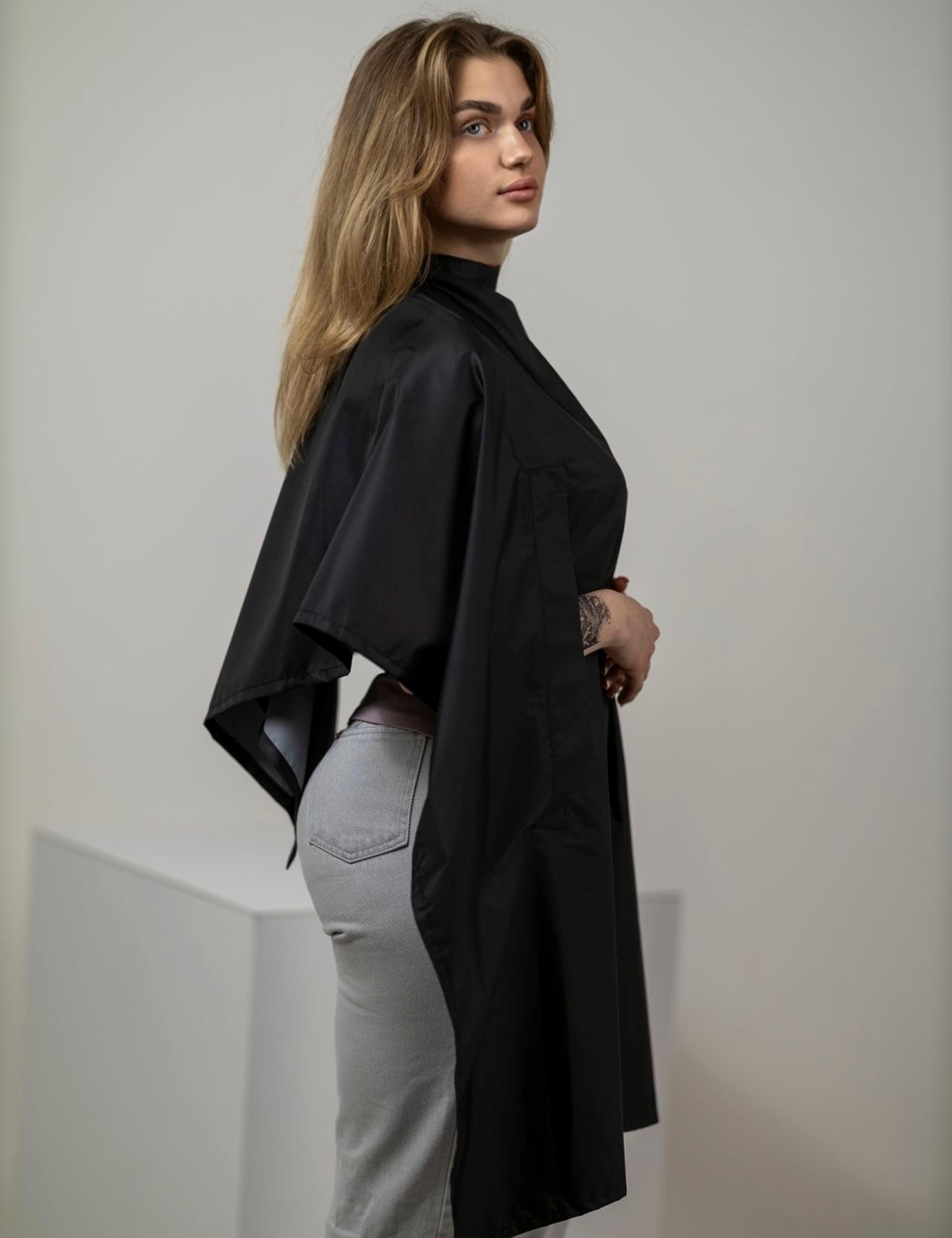 Black salon drape with hand slots protecting clothing during styling