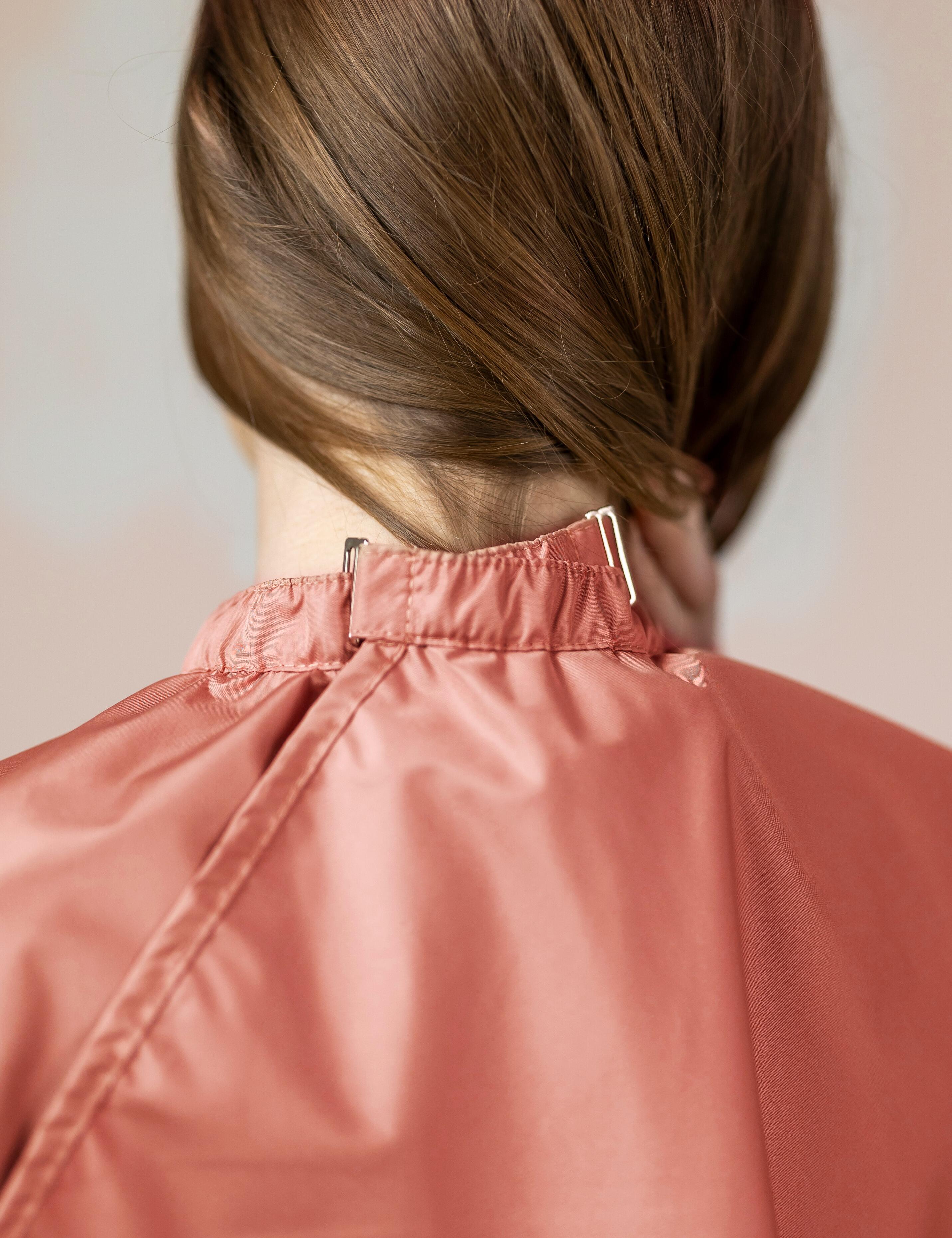 Peach salon cape with hand slits and secure clip closure