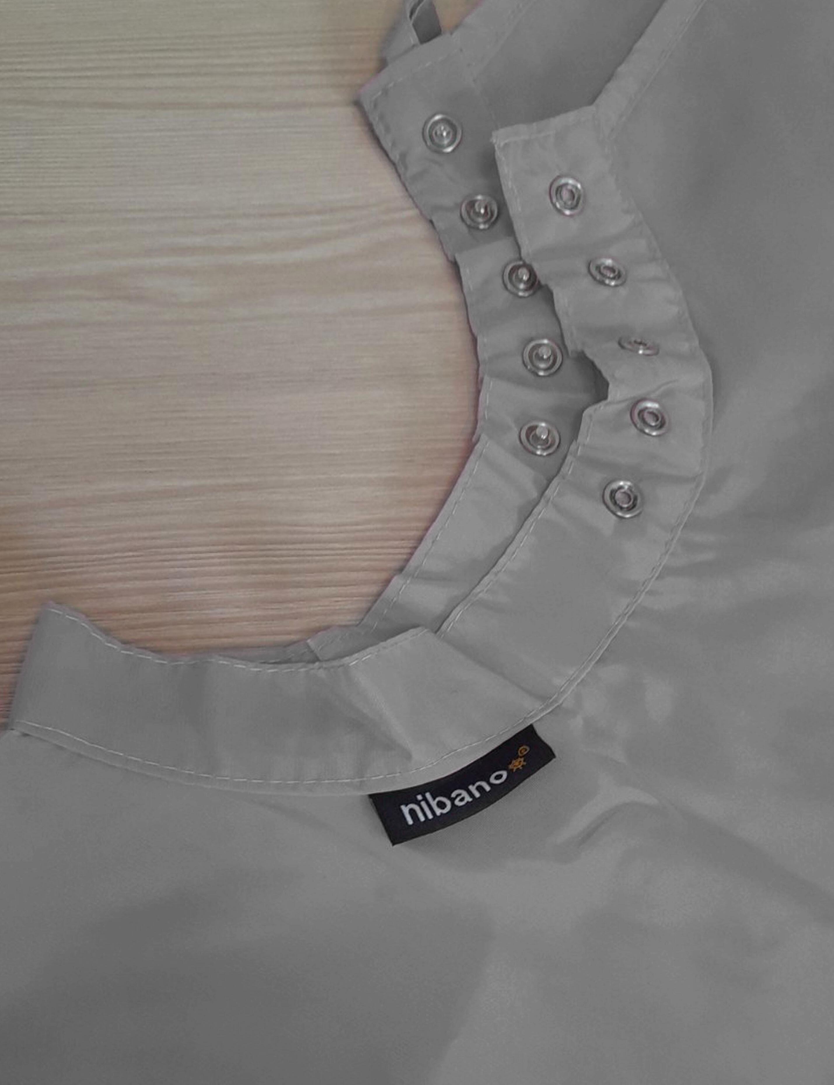 Grey salon cape with adjustable snap closures for a secure neck fit