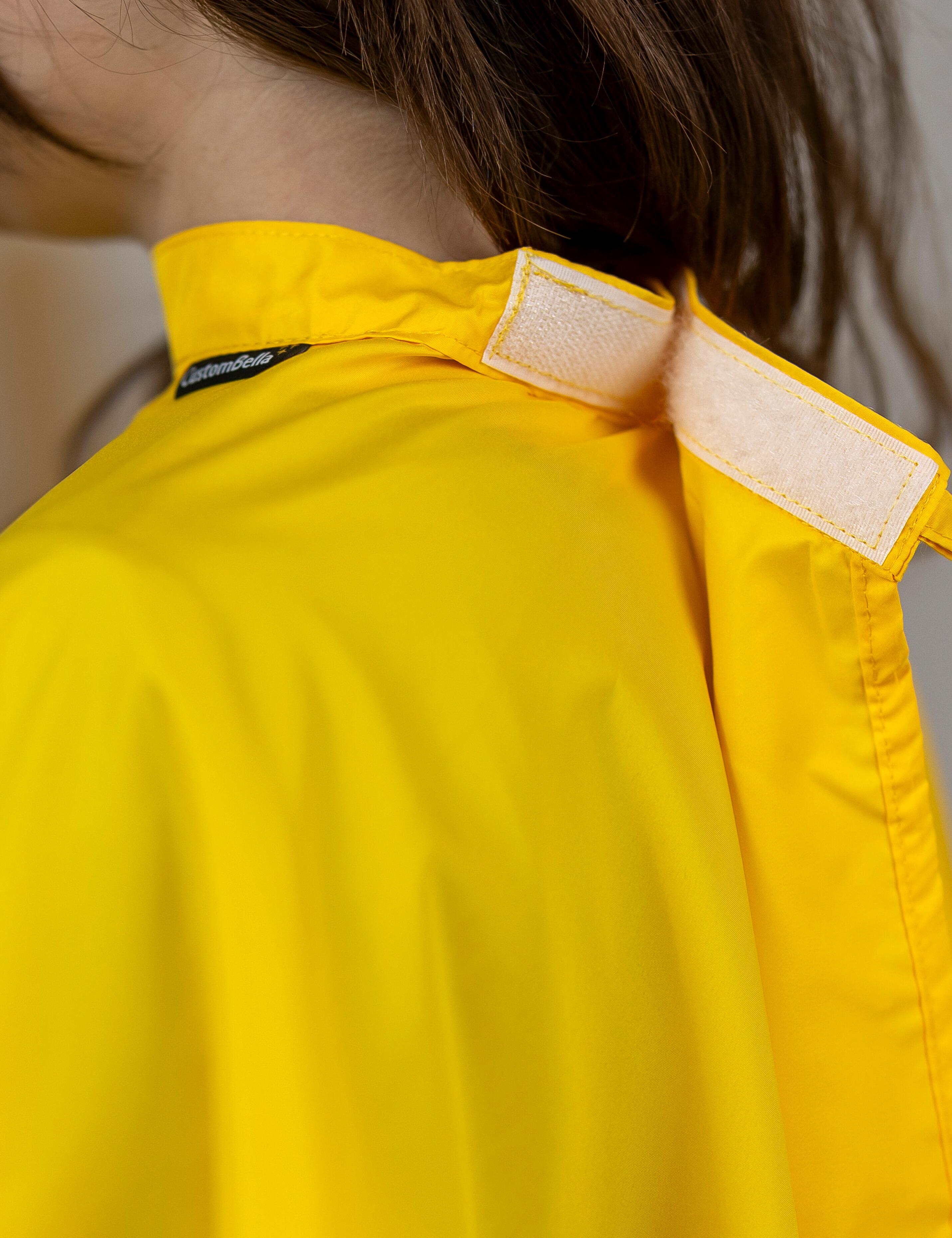 Yellow kids salon cape with an adjustable velcro neck closure