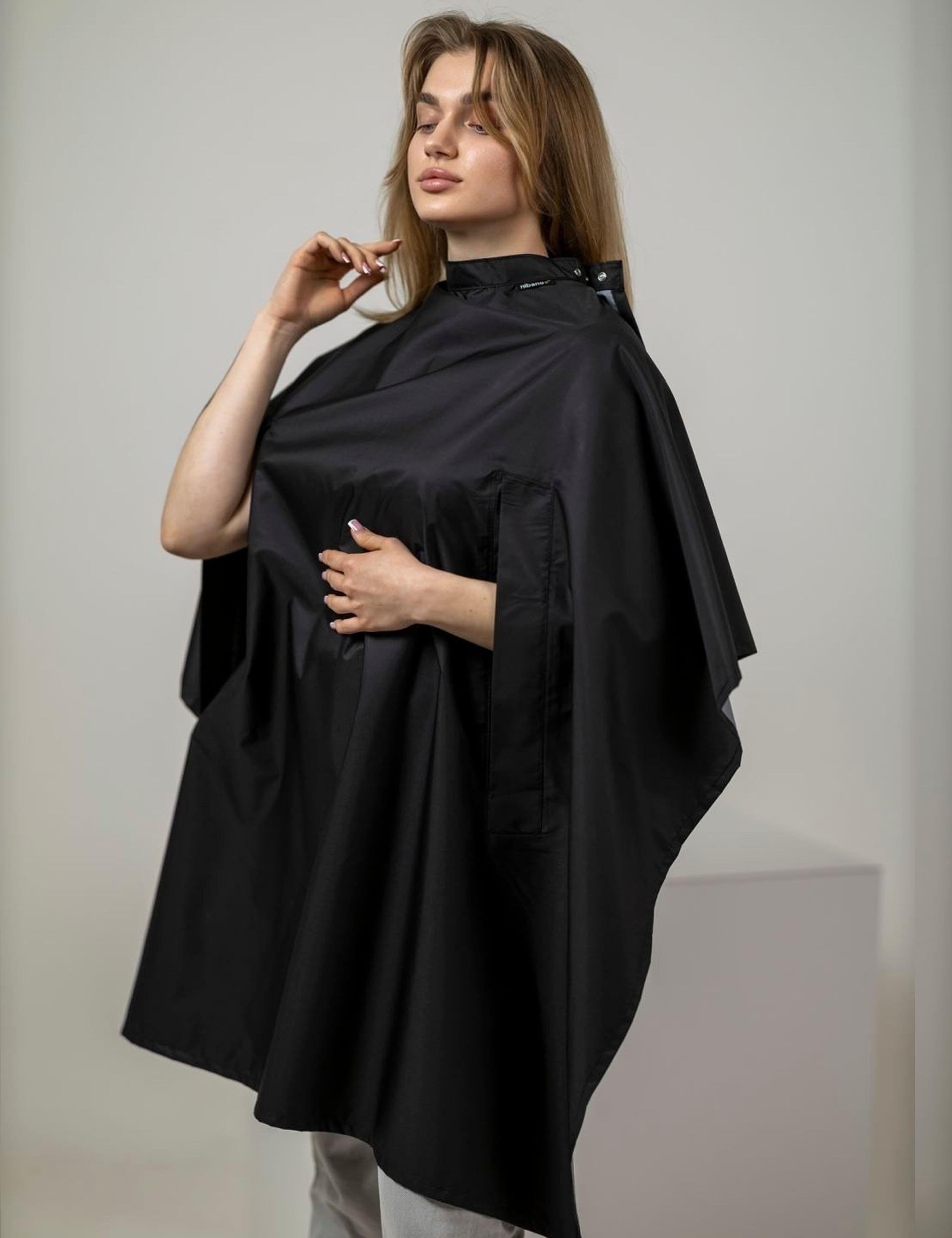 Plain black salon wrap with hand slits isolated on a solid backdrop