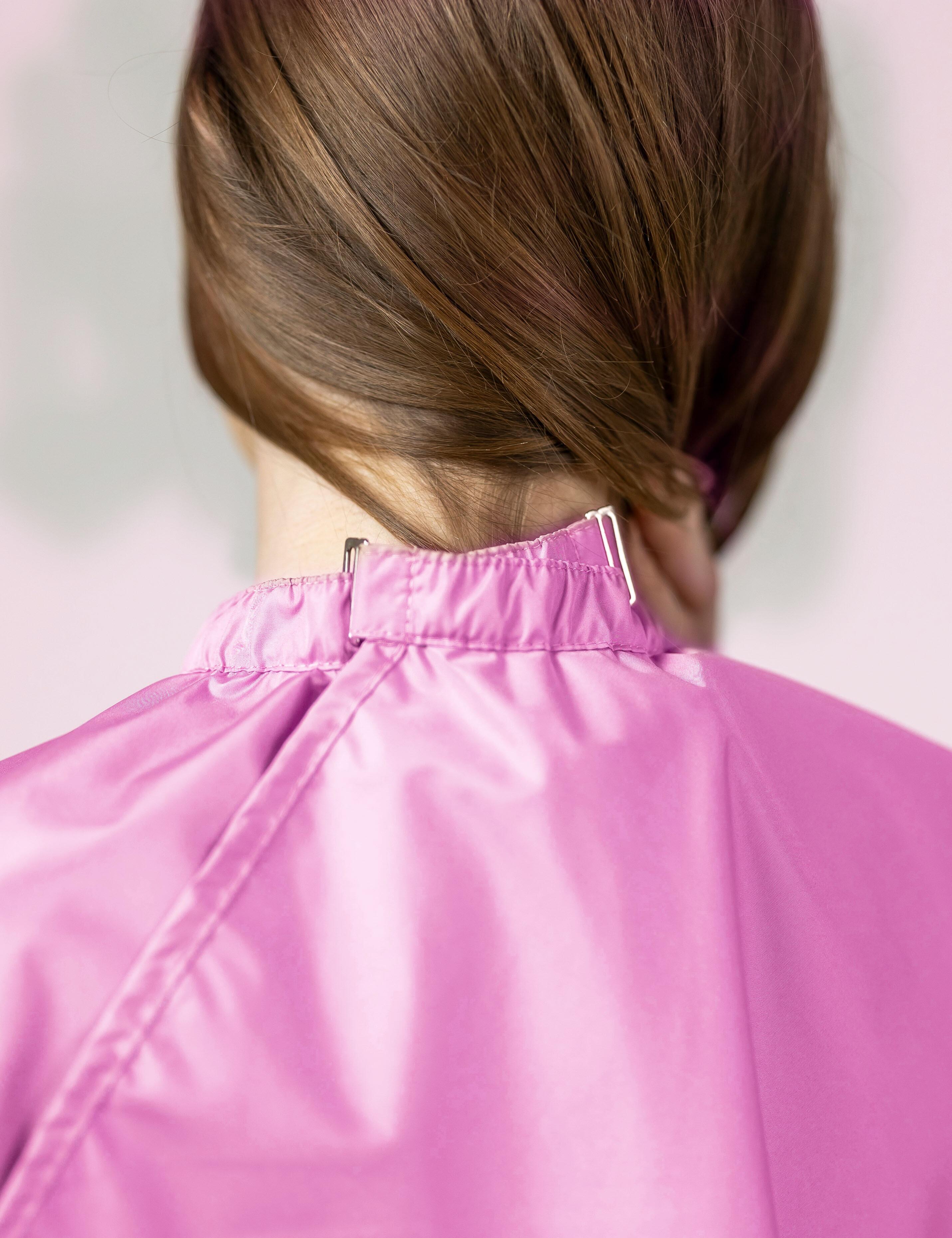 Pink salon cape with hand slits and secure clip closure