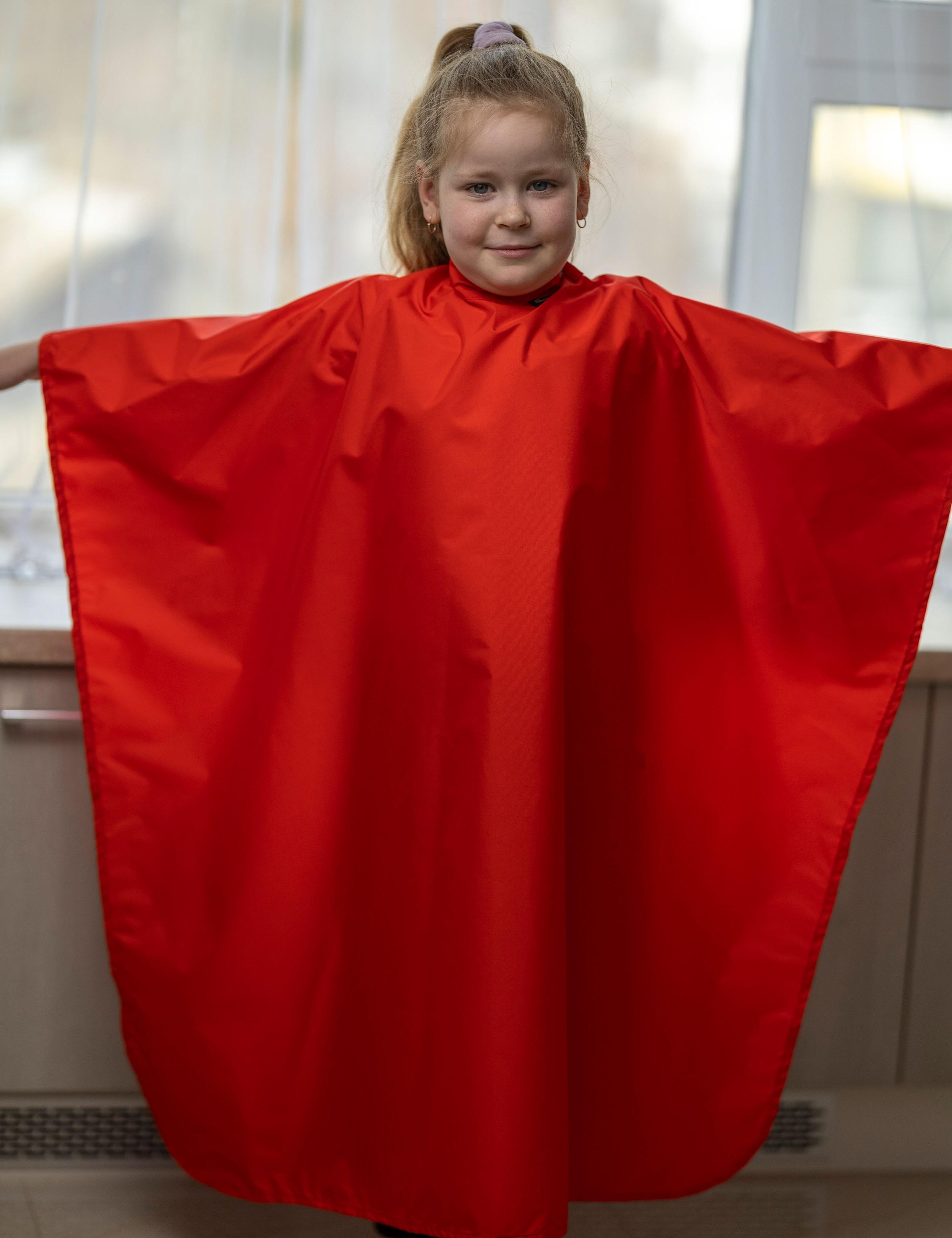 Classic red barber cloth keeping children clean during a hair trim