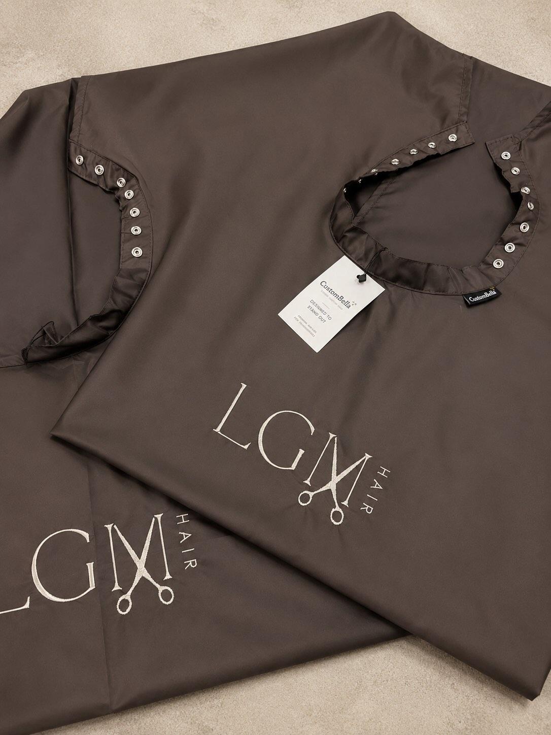 Premium embroidered chocolate salon cape featuring high-quality branding.