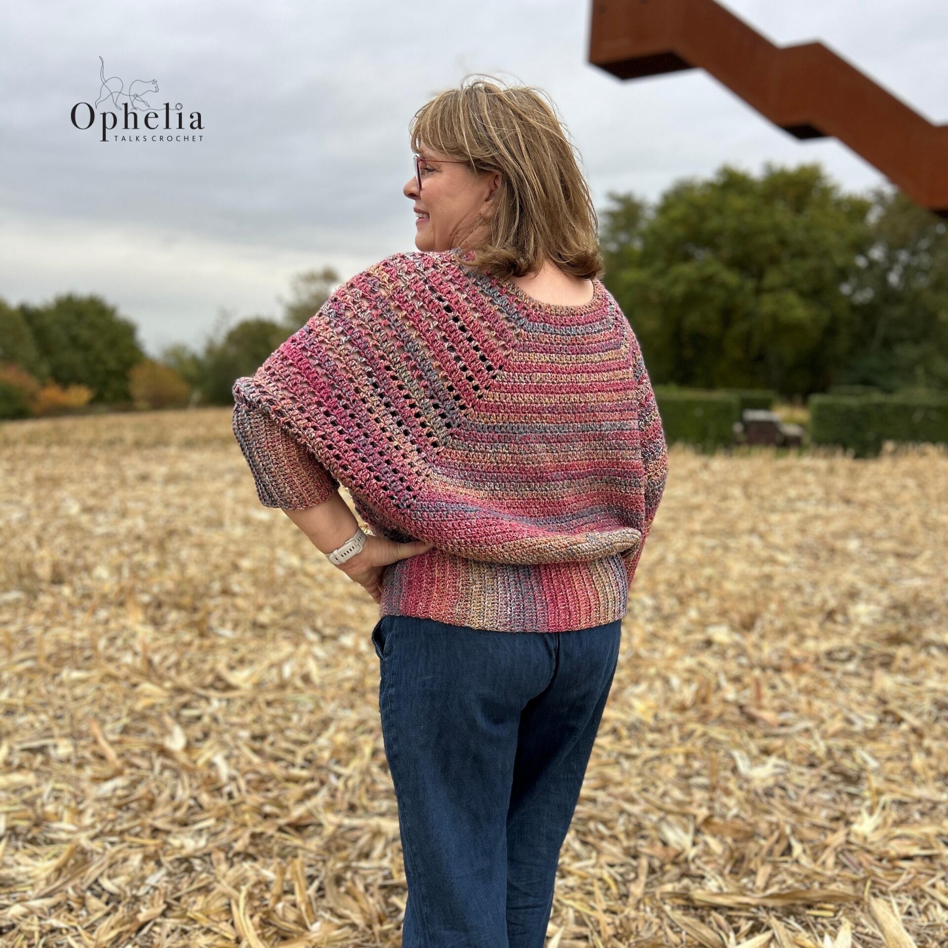 Back view of a handmade crochet batwing sweater in pink tones by Ophelia Talks Crochet, showing the relaxed fit and stitch texture.