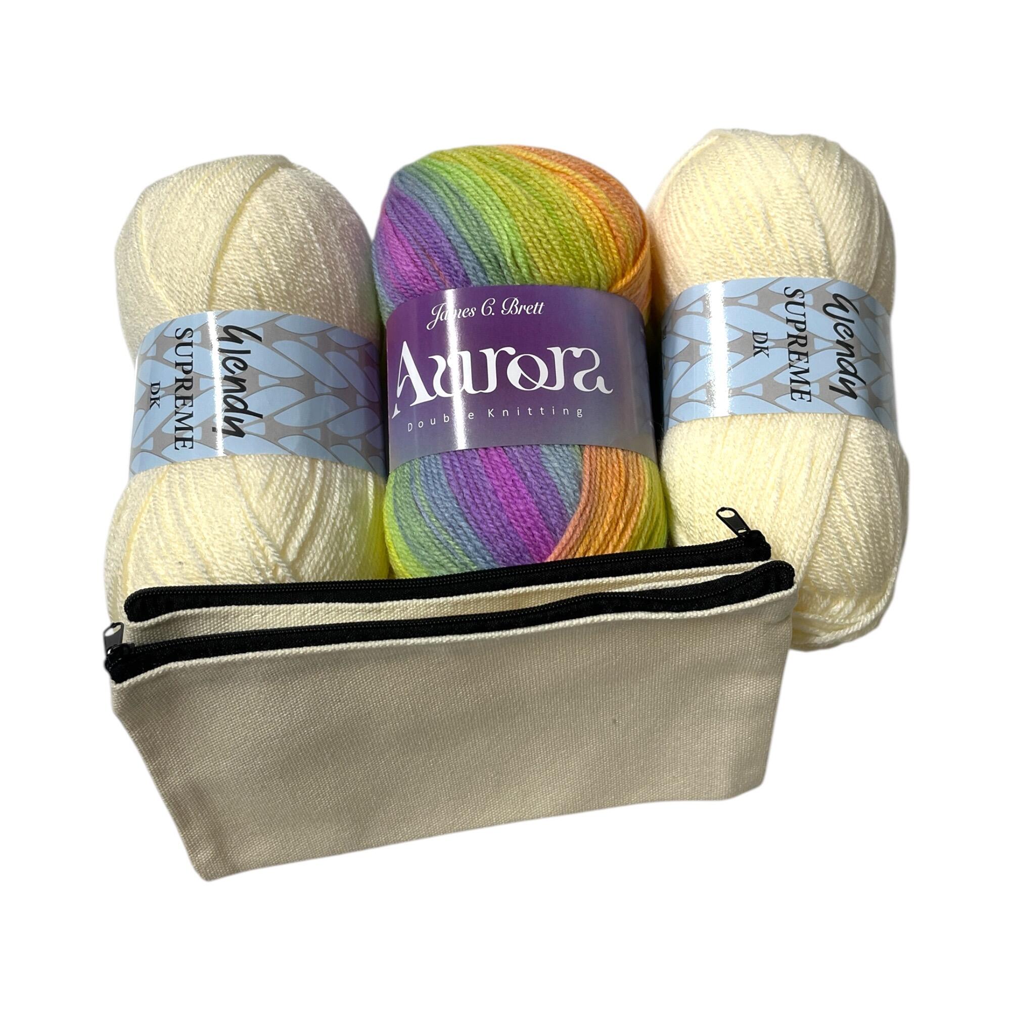 Crochet Pouch Kit featuring James C. Brett Aurora yarn in vibrant rainbow colors, Wendy Supreme DK yarn, and a cream-colored zipper pouch.
