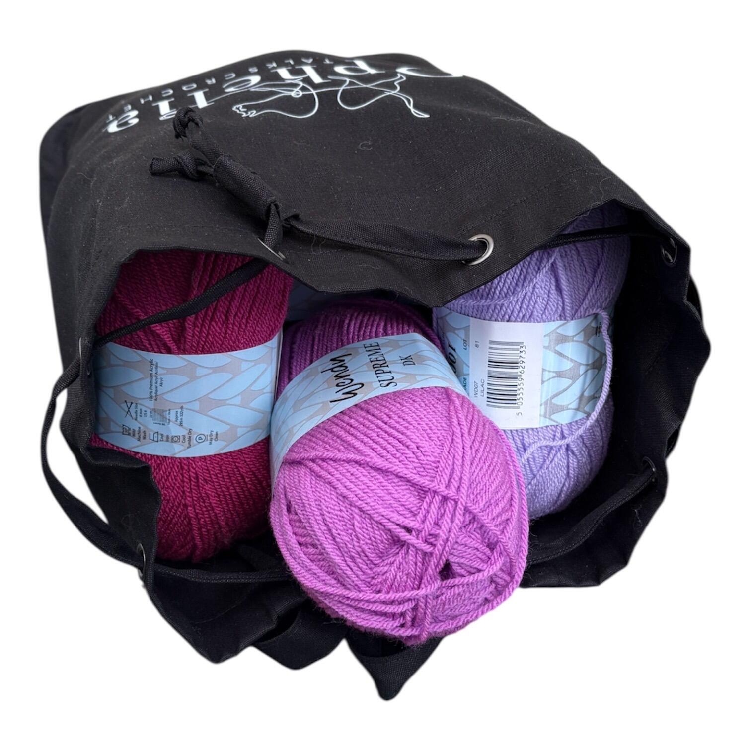 Ophelia Talks Crochet black canvas backpack open with pink and purple yarn balls inside showing spacious interior for 12 x 100g balls.