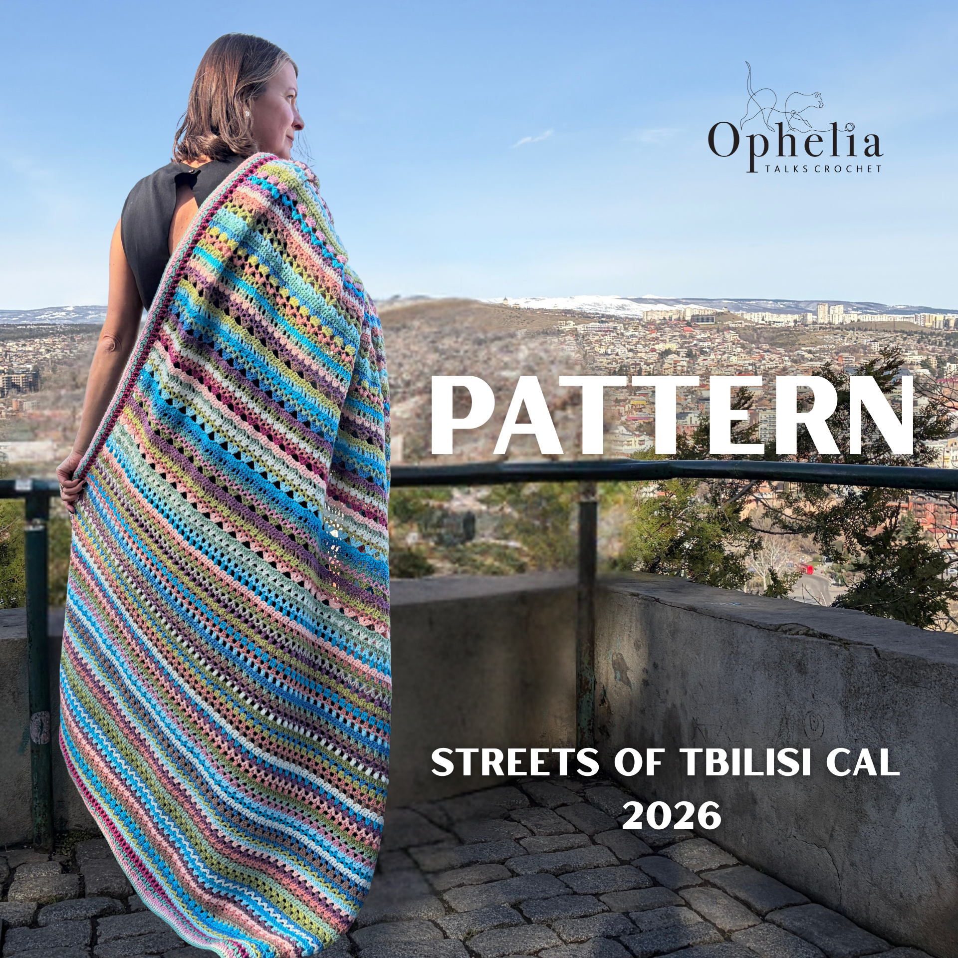 Woman wearing a colourful striped crochet blanket stands on a balcony overlooking the city of Tbilisi, with mountains in the distance. The image includes the Ophelia Talks Crochet logo and the text “Pattern – Streets of Tbilisi CAL 2026