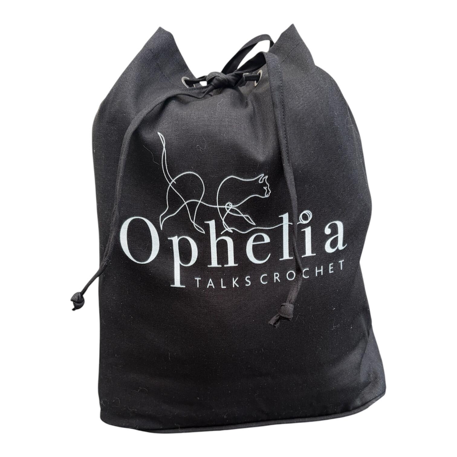 Front view of Ophelia Talks Crochet black canvas backpack with white logo and drawstring closure.