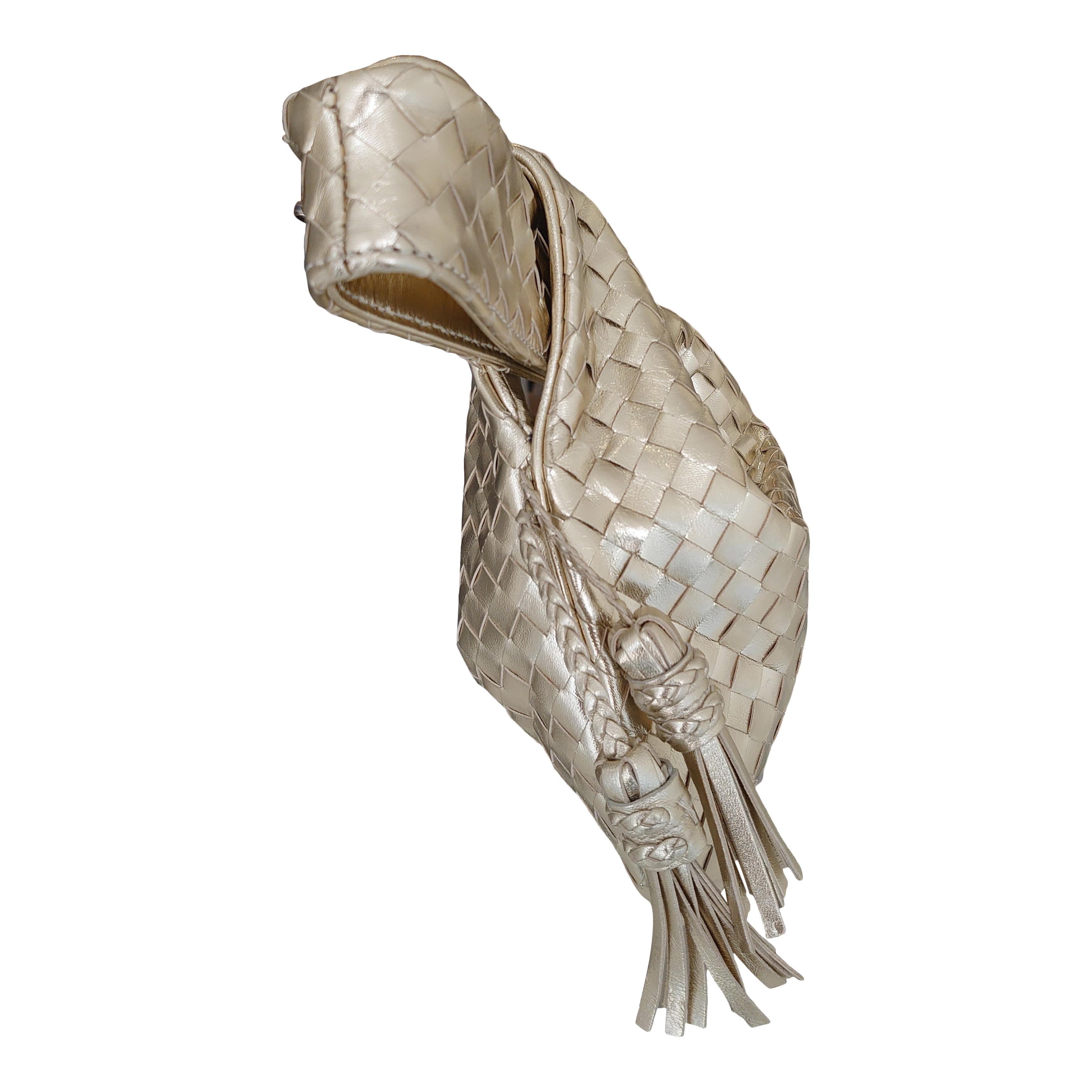 Exquisite small intrecciato evening bag in gold, with a knot at the top and two small tassels.