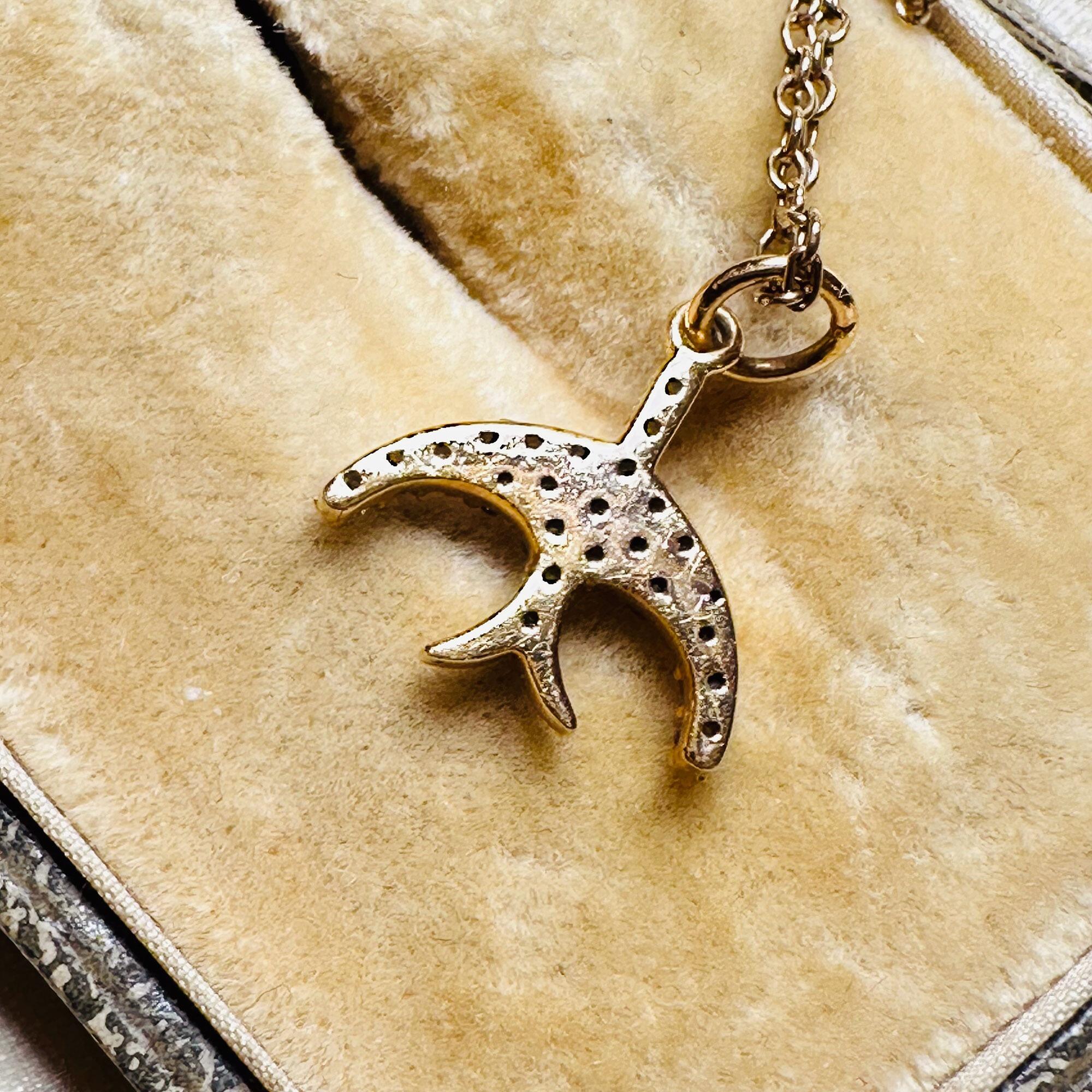14ct Rose Gold & Diamond Swallow Charm Pendant with chain laying on antique box.