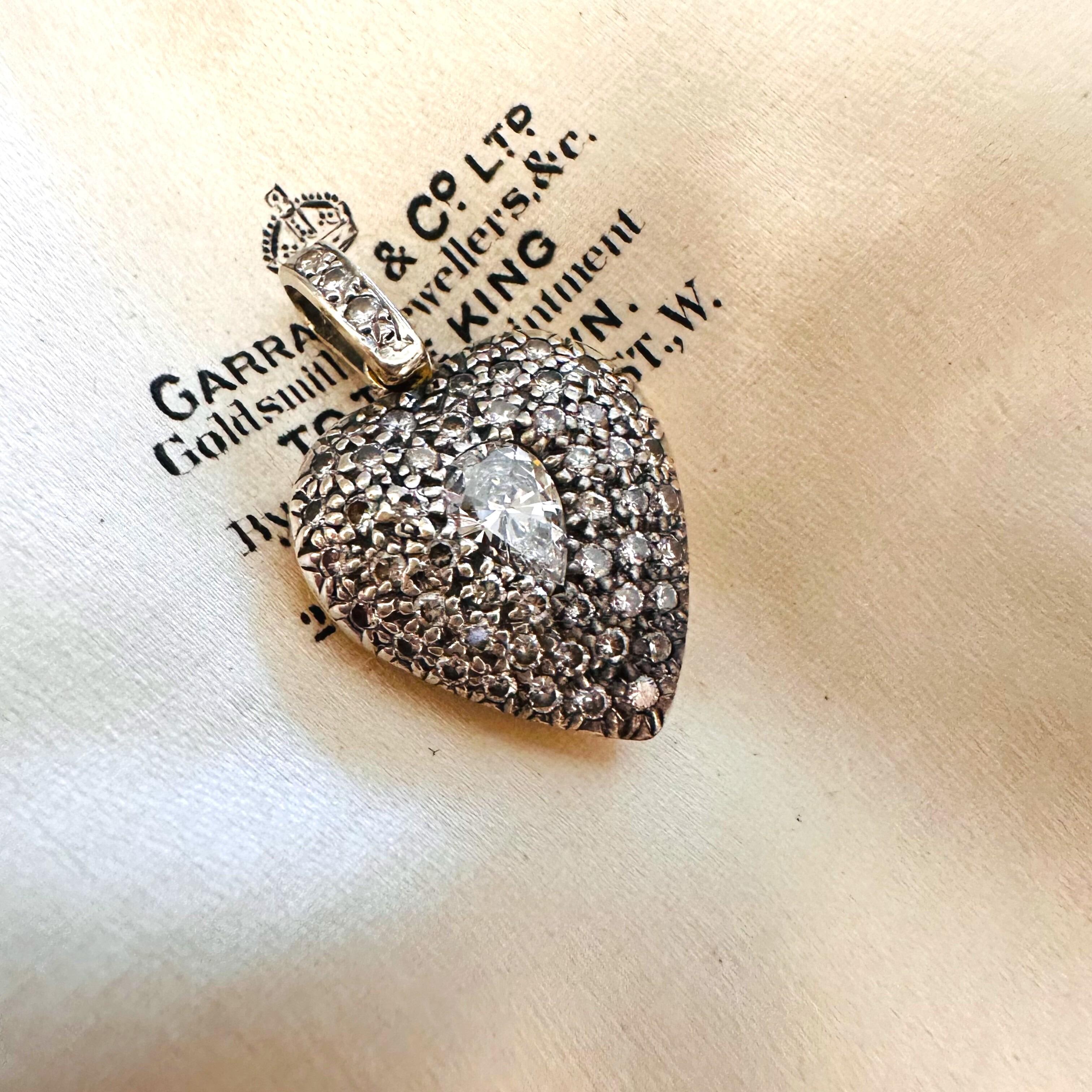 Diamond Heart Locket Pendant with Pear-Shaped Center displayed on a antique box