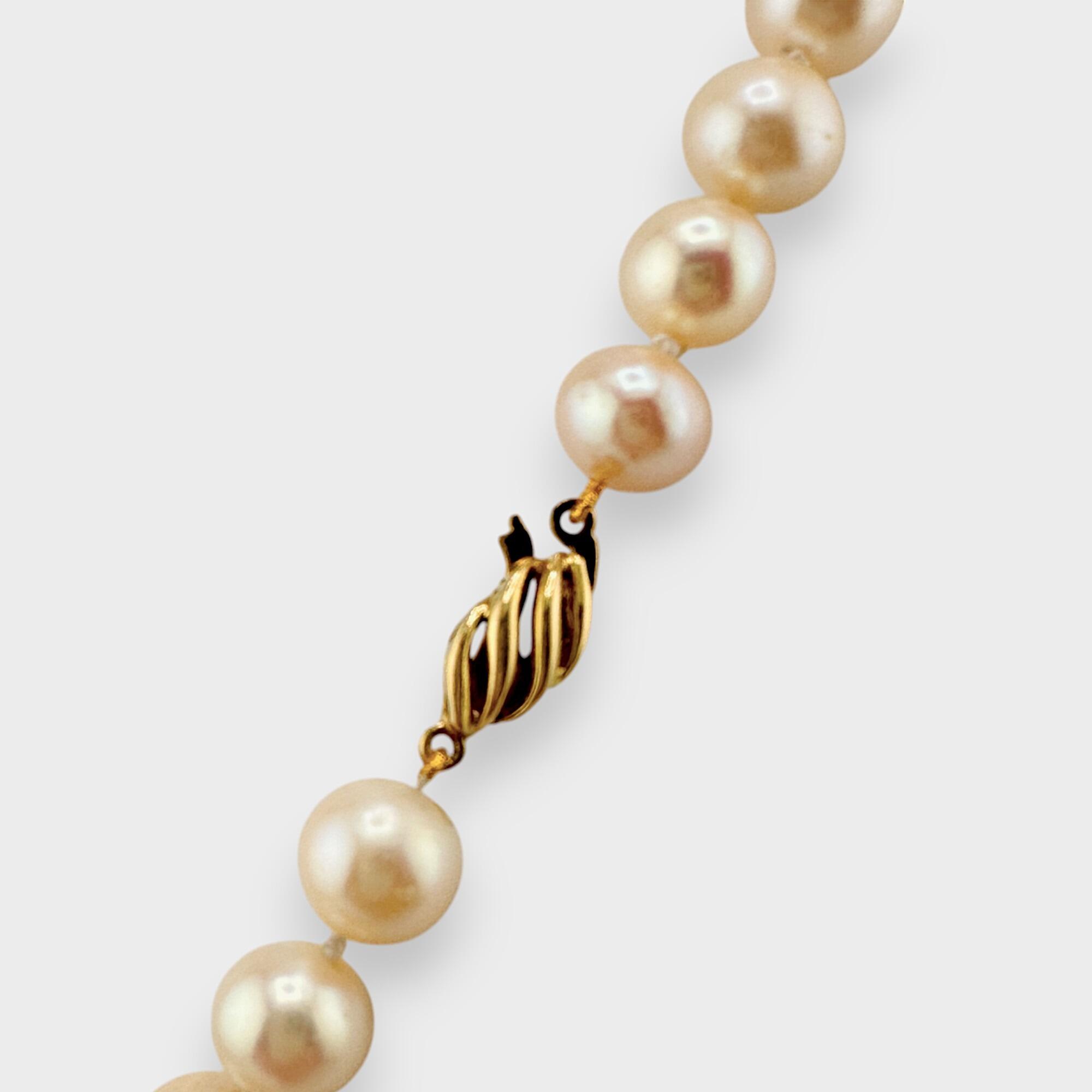 Side view of white pearl necklace with gold fastening detail