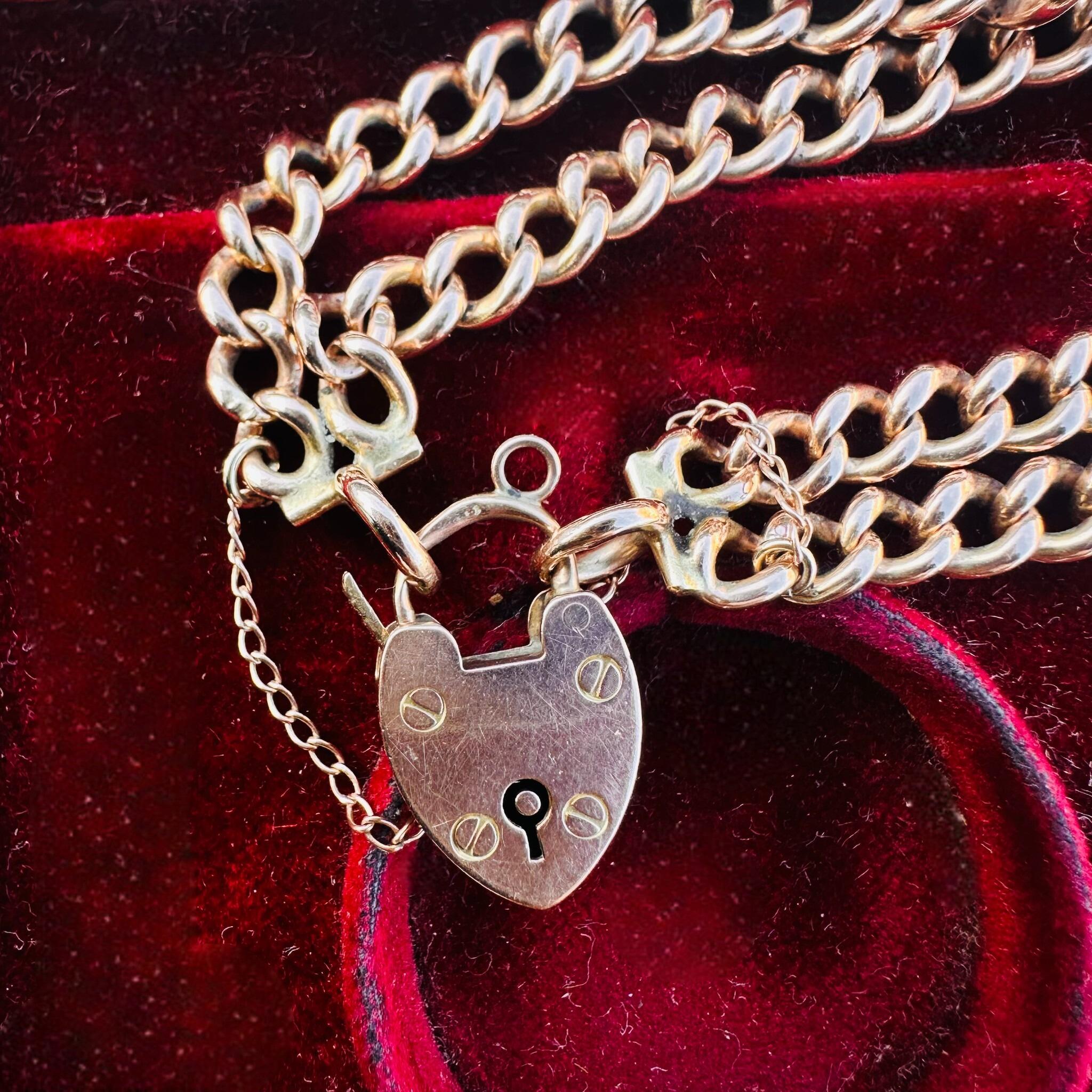 Rose Gold Double Curb Link Bracelet with Heart Padlock, displayed on antique box.