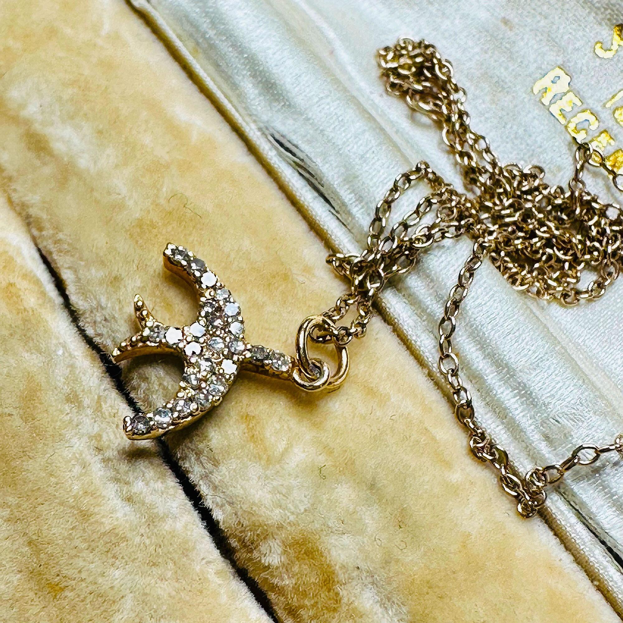 14ct Rose Gold & Diamond Swallow Charm Pendant with chain laying on antique box.