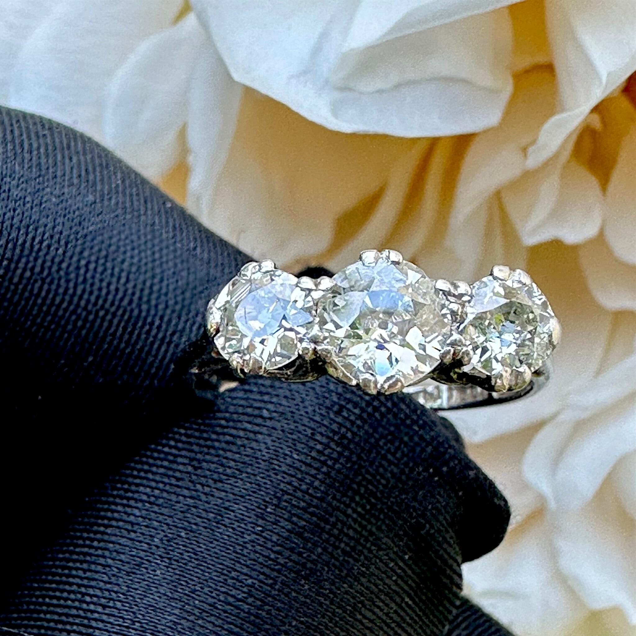 Antique Art Deco18K White Gold & Platinum, Old European Cut Diamond Trilogy Ring held in gloved hand with garden background