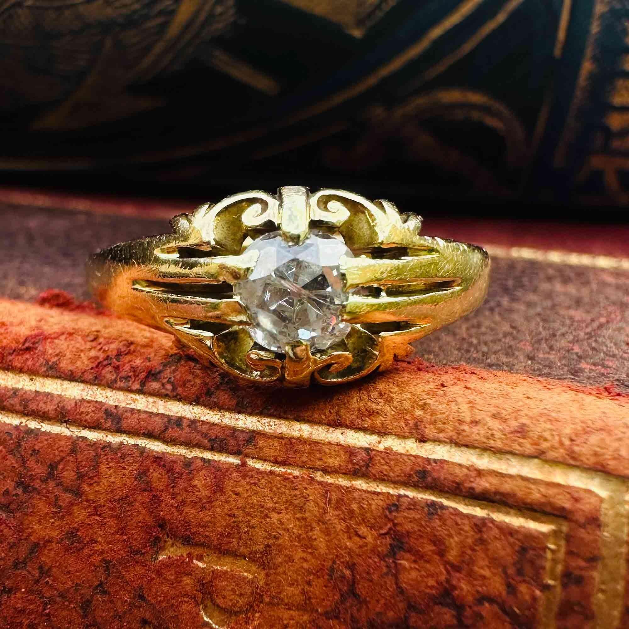 Antique 18k yellow gold old cut diamond gypsy ring on edge of book.