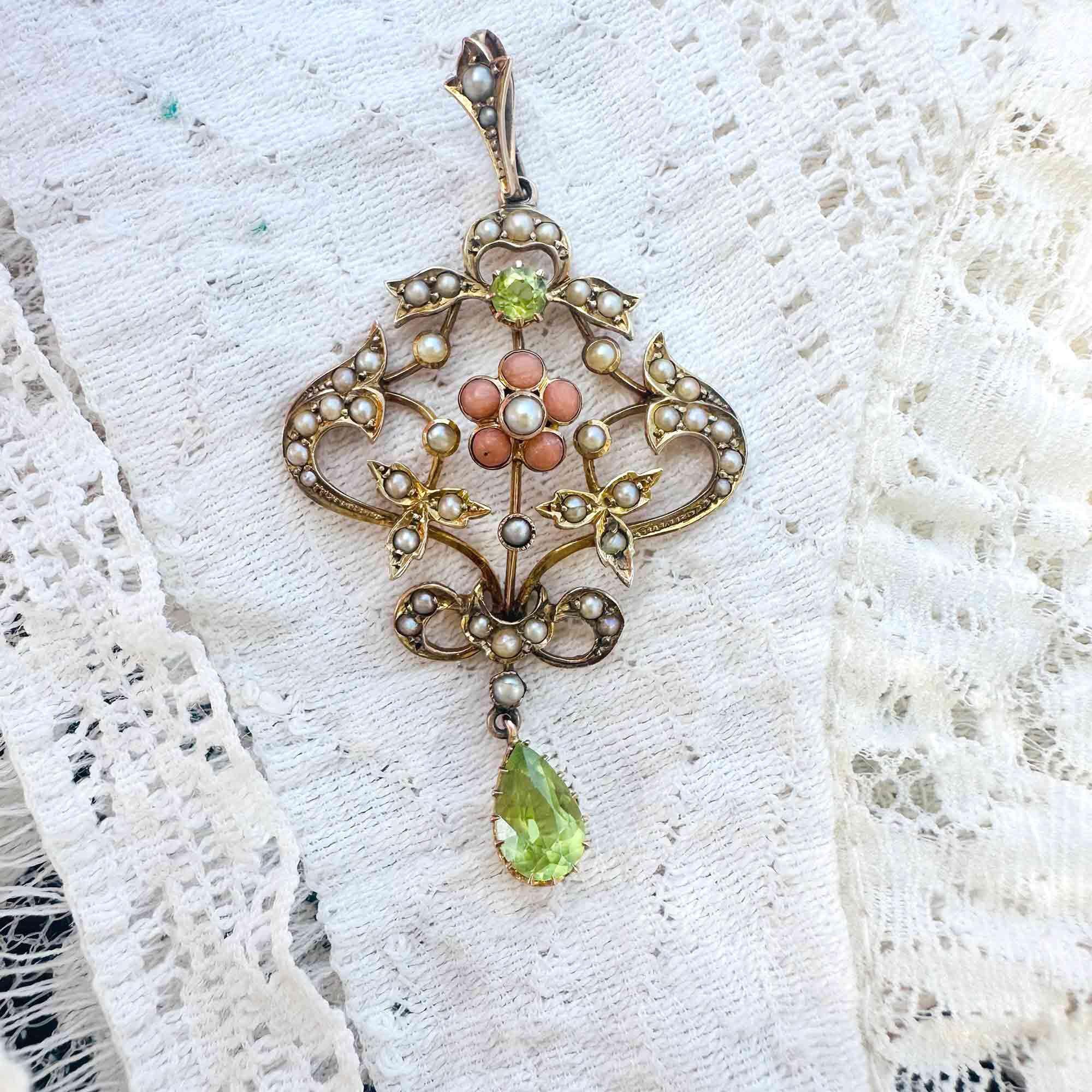 Art Nouveau 9k gold Lavaliere Pendant Peridot & Pearl Floral Motif, displayed on cream lace