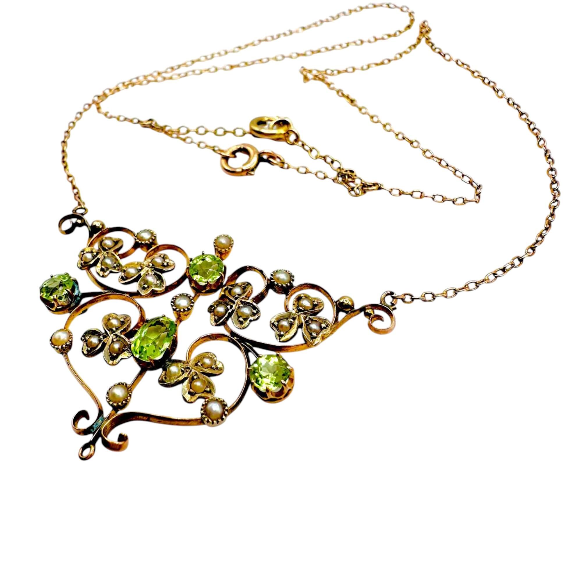 side view of Art Nouveau 9ct gold lavalier necklace with scrollwork, four peridot gemstones, and seed pearl foliate motif