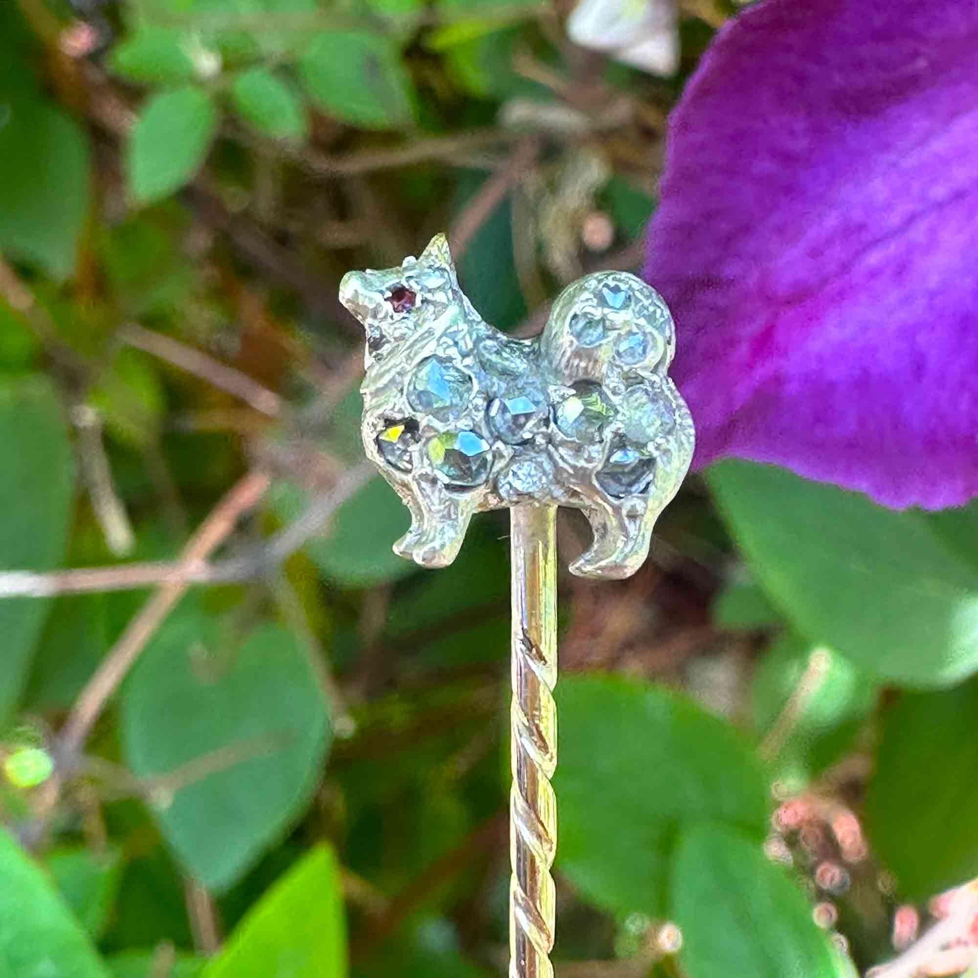 19th-century stick pin with Pomeranian dog motif and rose cut diamonds, garden background.